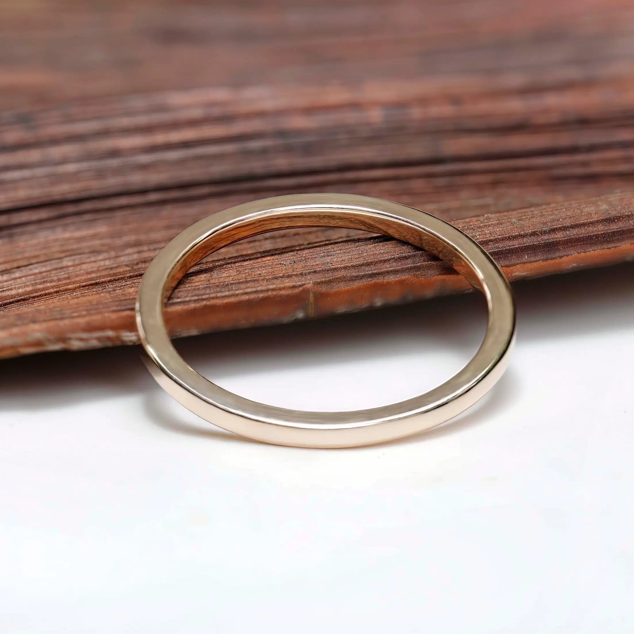 Polished gold band angled view resting on wooden background
