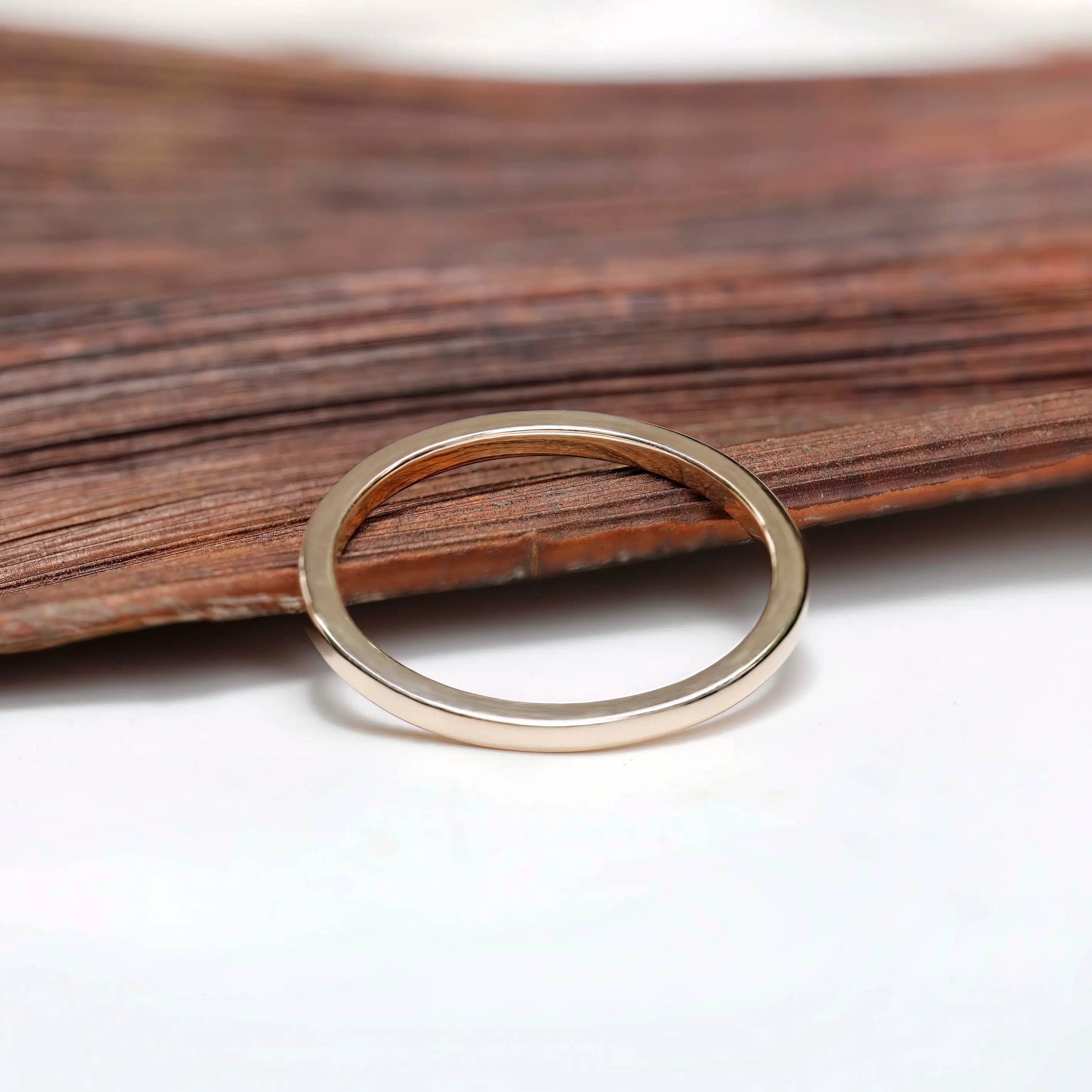 Polished gold band angled view resting on wooden background