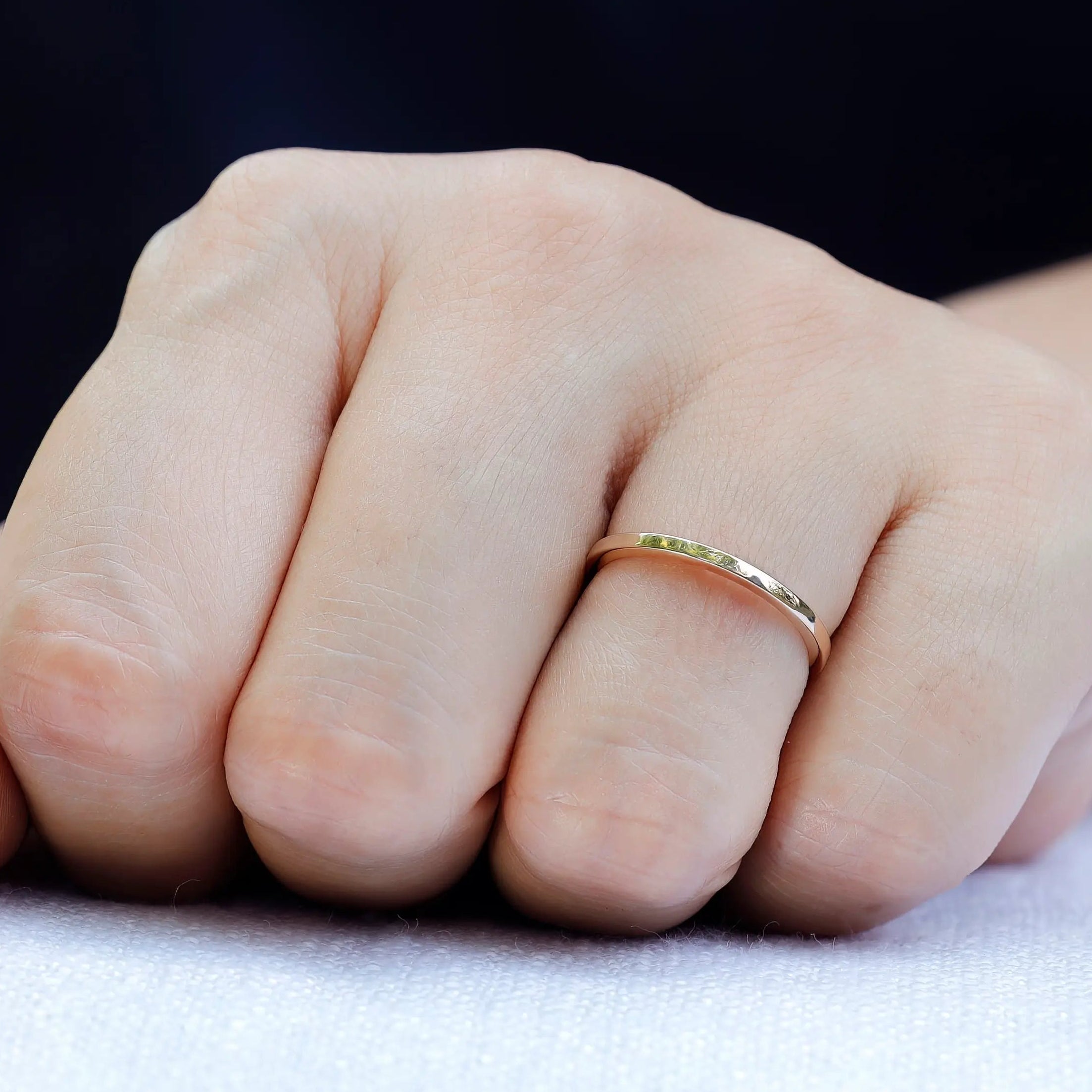 Simple gold wedding band showing circular profile worn on finger