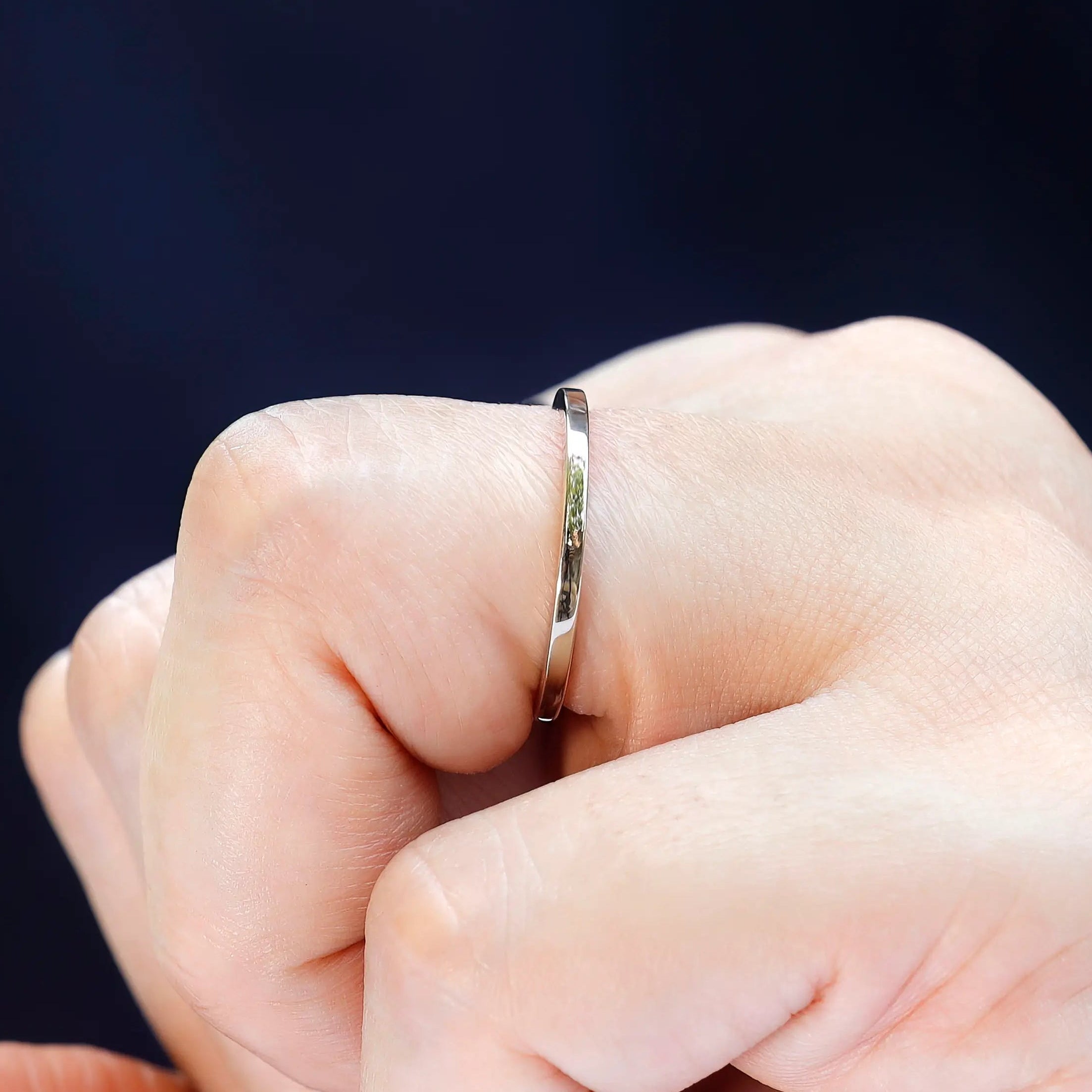 Close-up of thin polished gold wedding band worn on finger