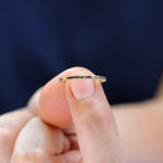 Minimal gold band held on fingertip showing slim width and smooth finish