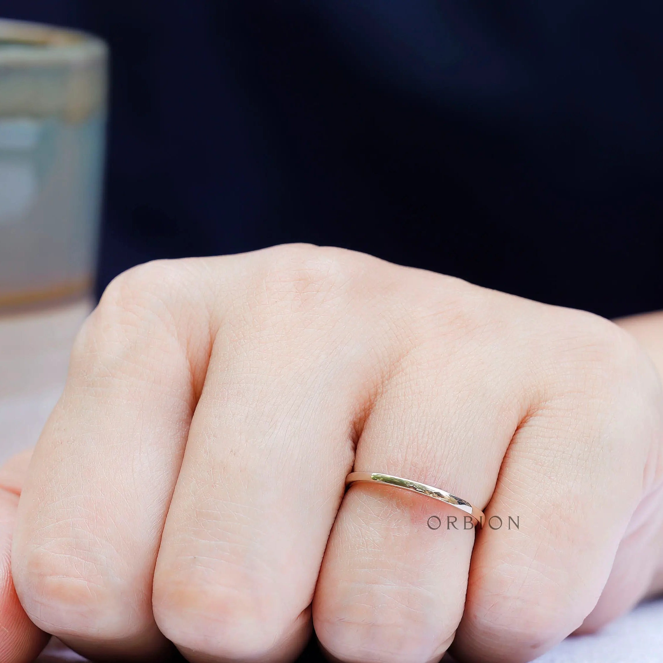 Minimal gold wedding band on hand highlighting thin and delicate profile