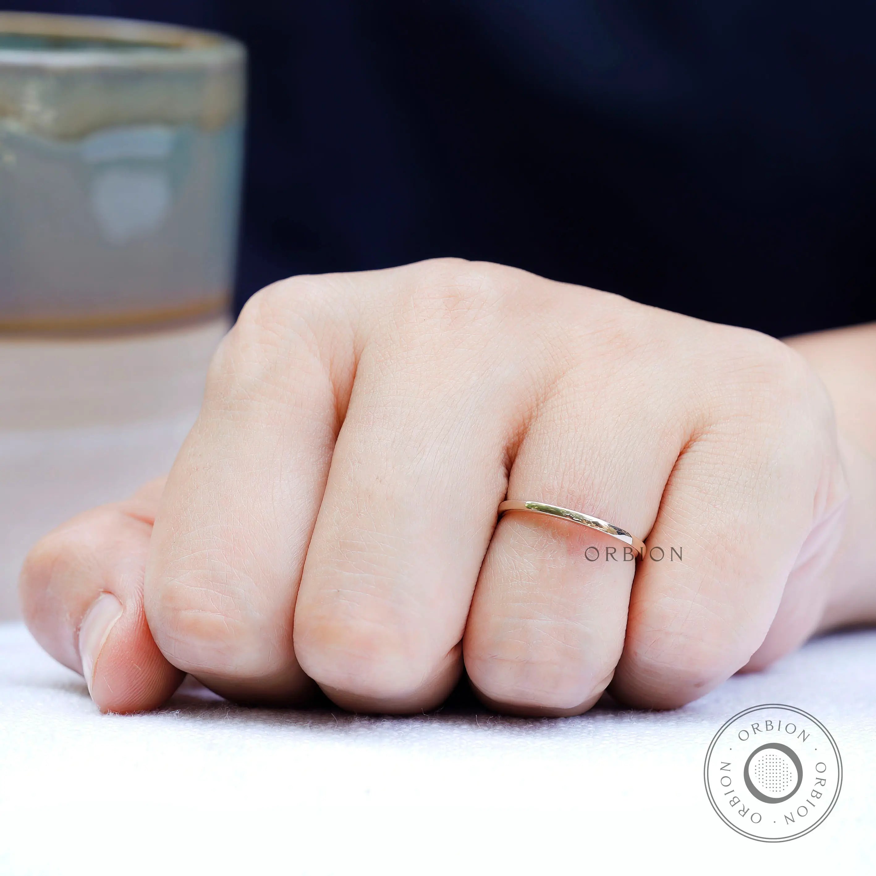 Minimal gold wedding band on hand highlighting thin and delicate profile