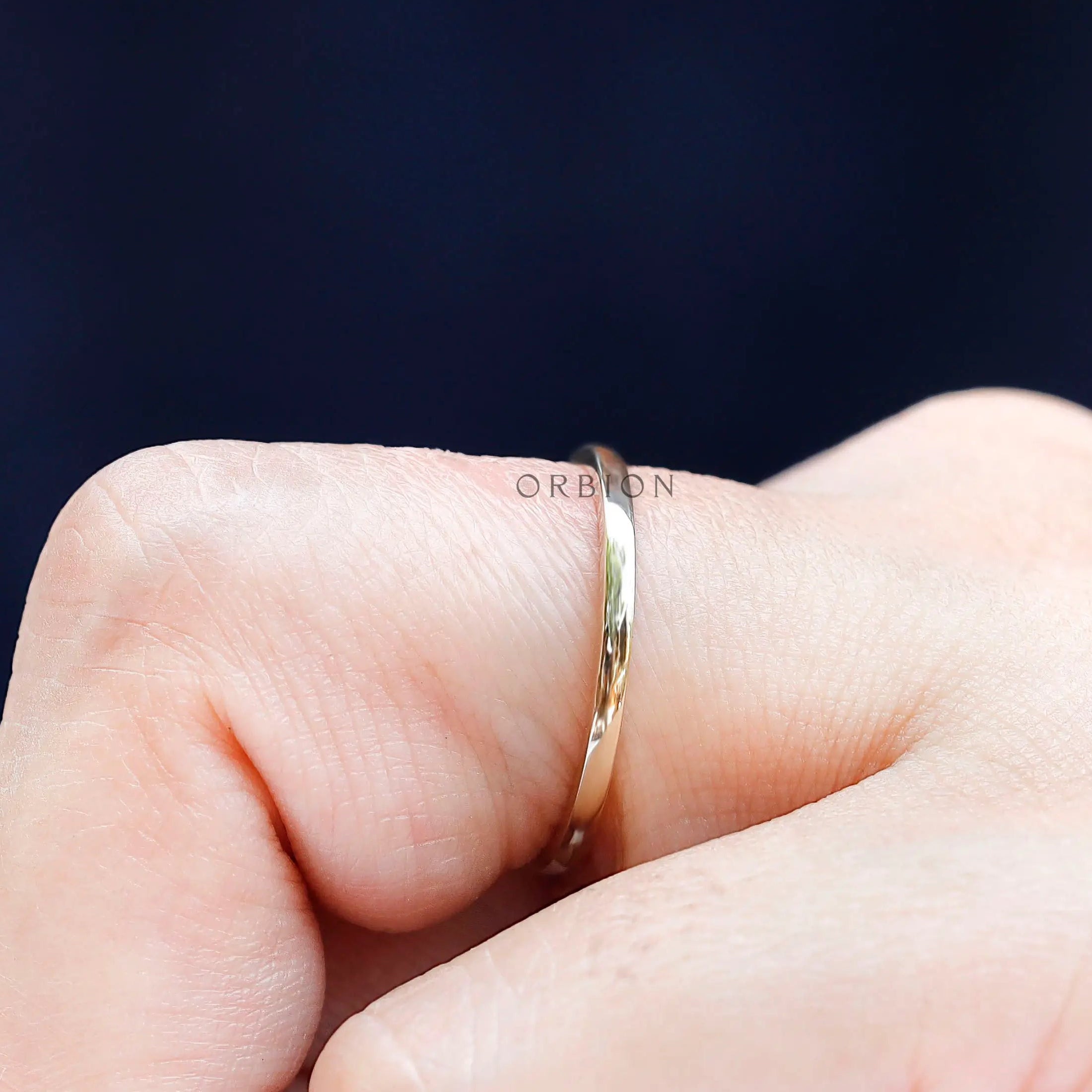 Close-up side view of thin gold stacking ring worn on finger
