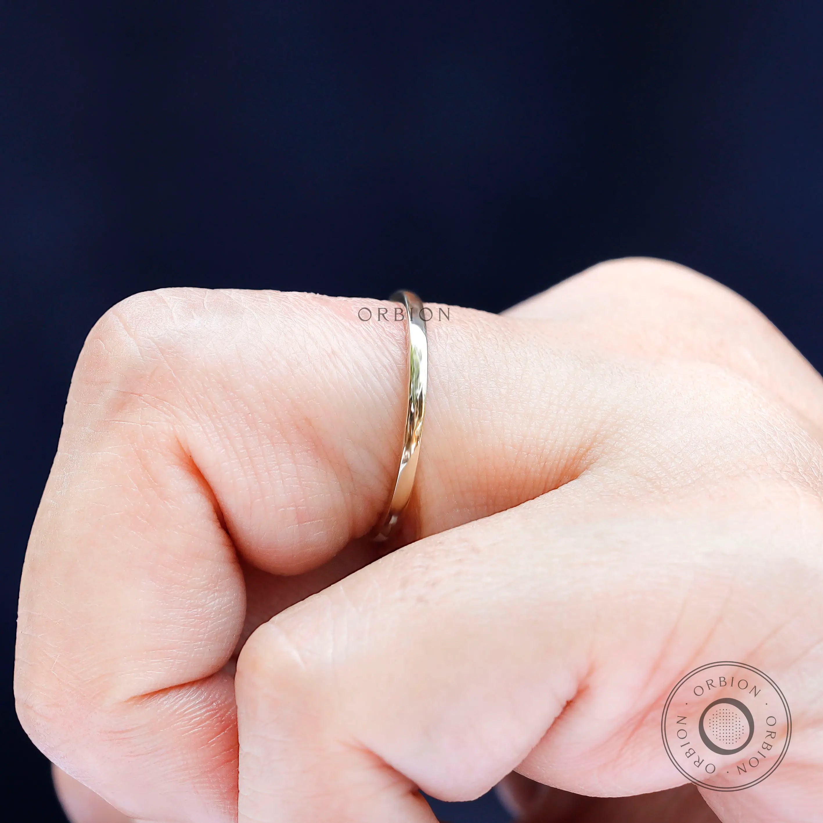 Close-up side view of thin gold stacking ring worn on finger