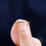 Ultra slim polished gold band shown between fingers to highlight fine width