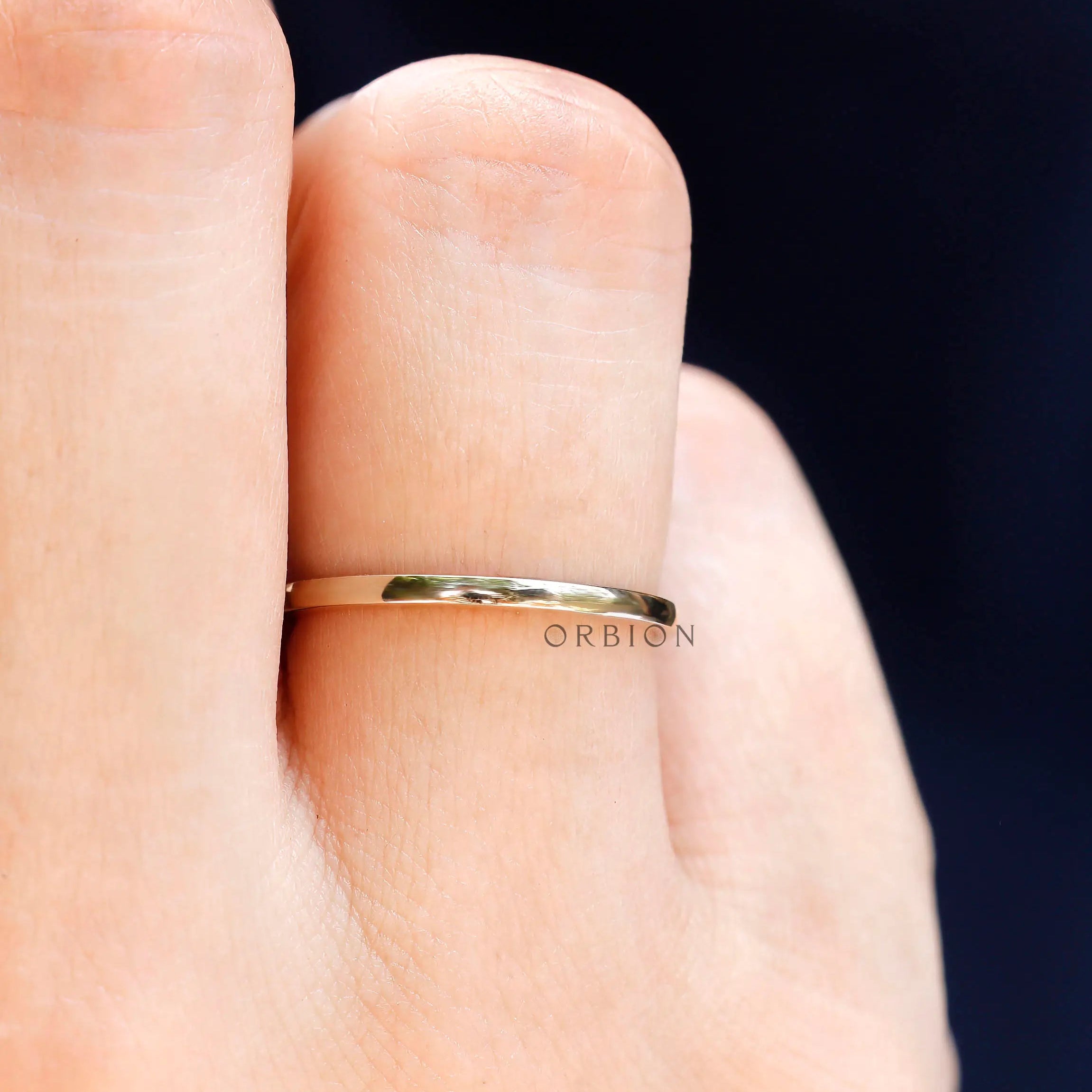 Minimalist plain gold wedding band worn on finger with smooth polished finish