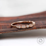 Angled front view on wooden surface marquise and round motif moissanite band