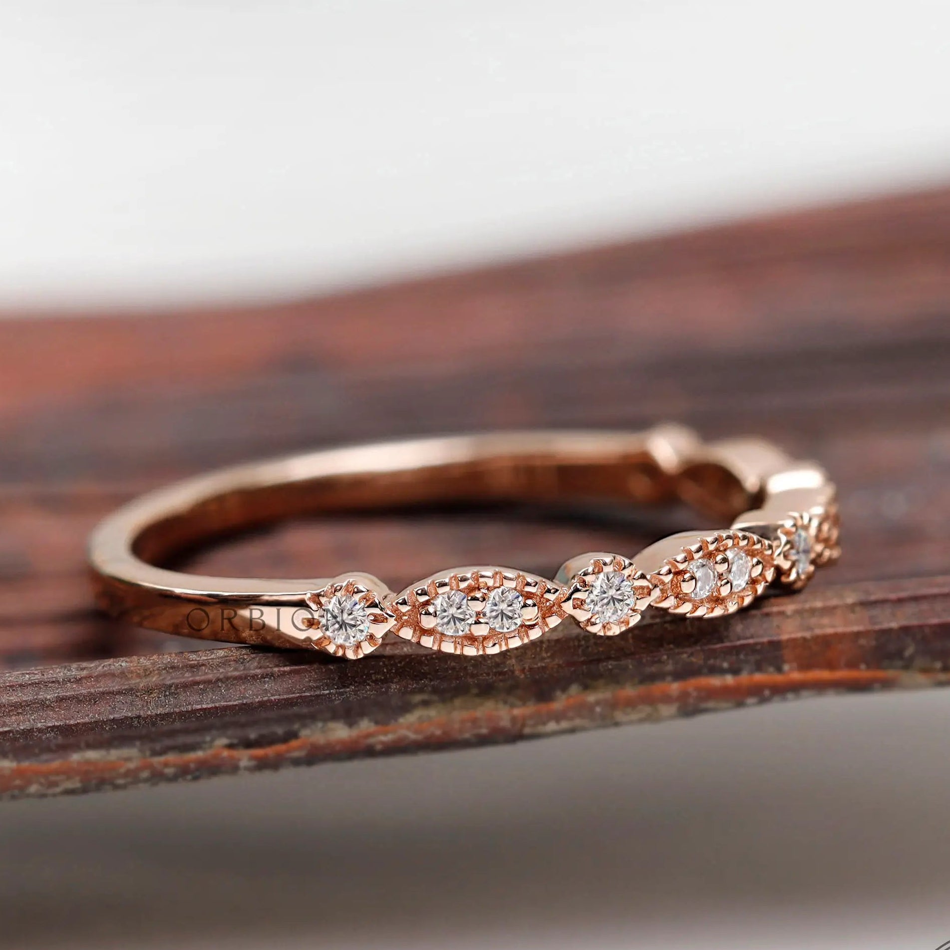 Angled front view on wooden surface marquise and round motif moissanite band