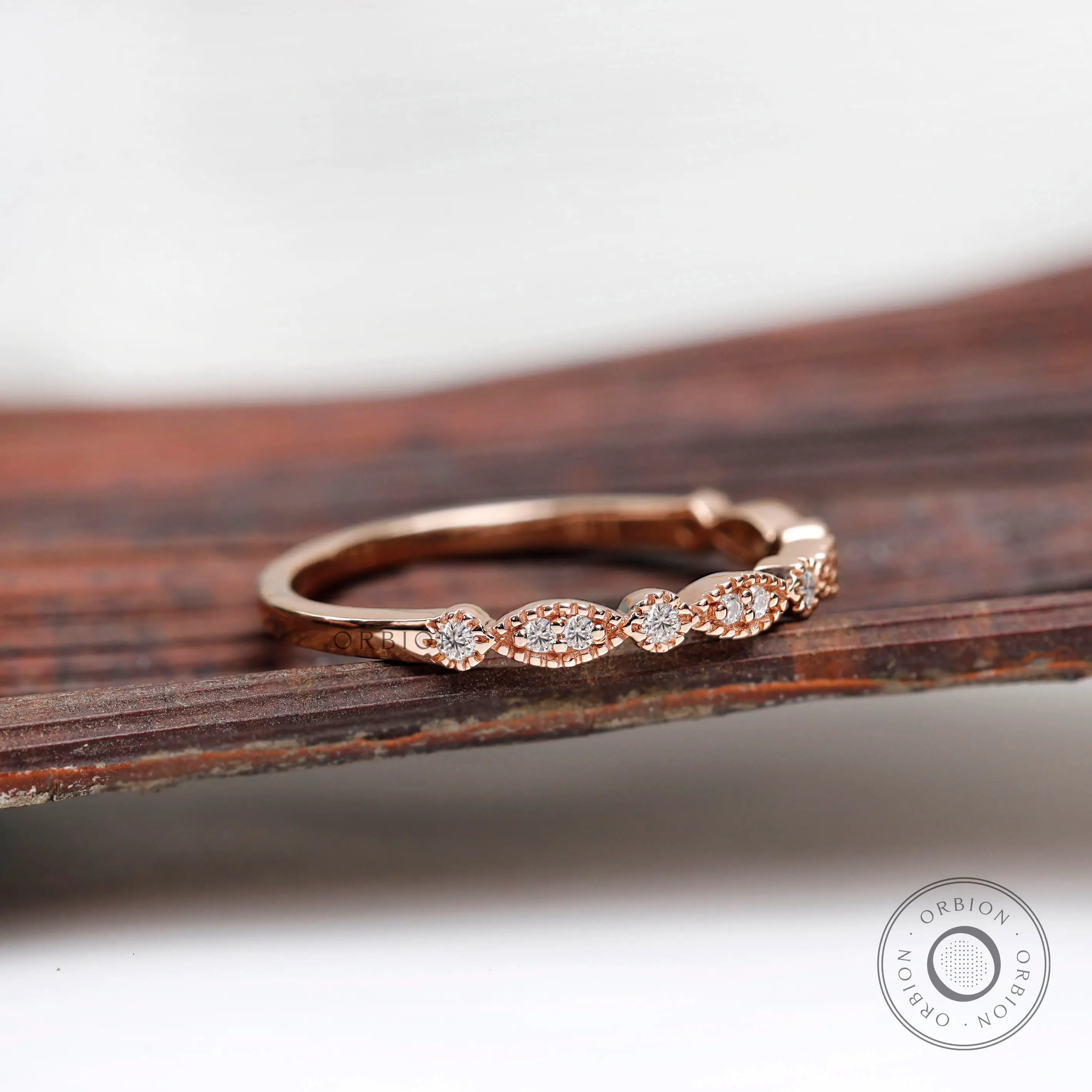 Angled front view on wooden surface marquise and round motif moissanite band