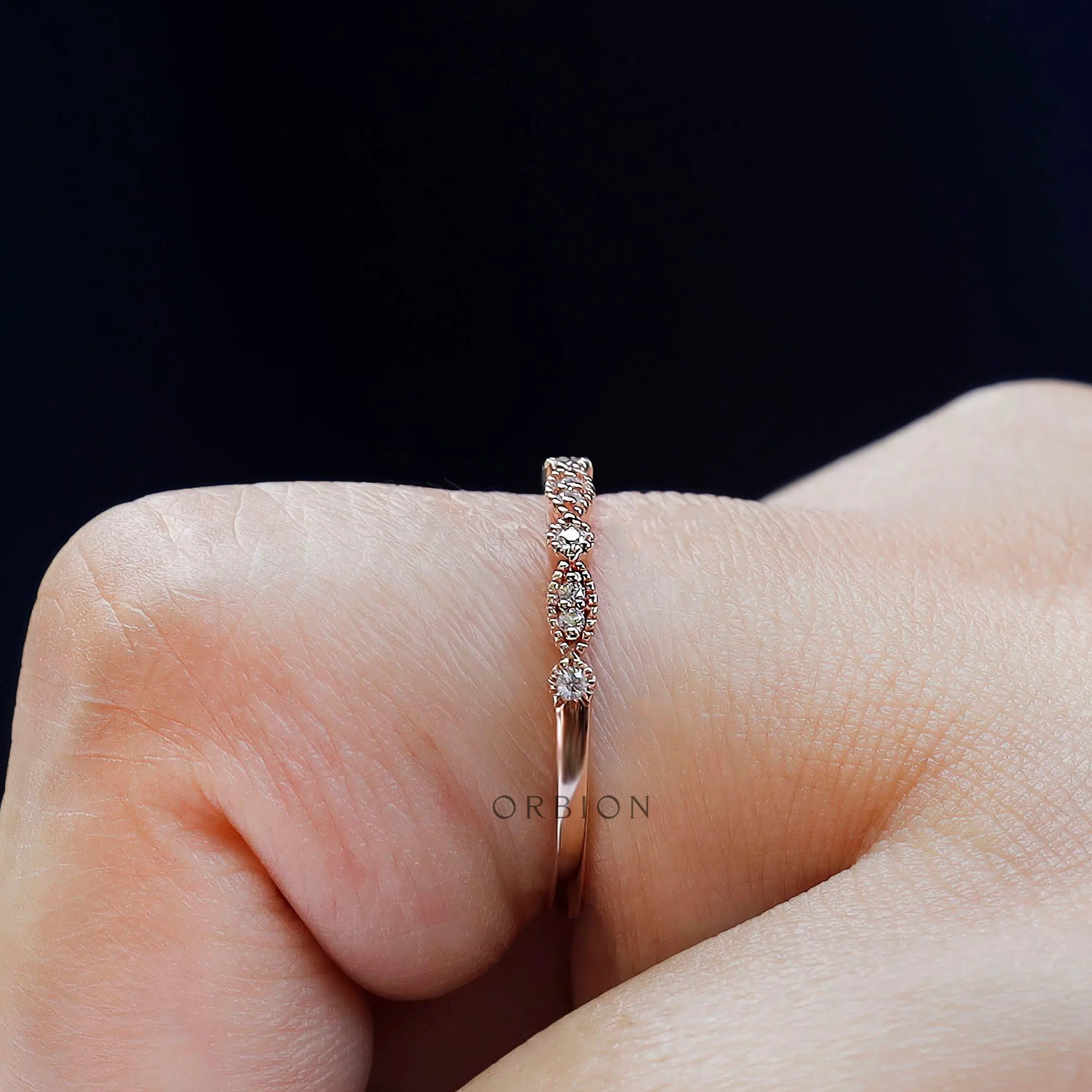 Close-up of marquise link and round moissanite milgrain band worn on finger
