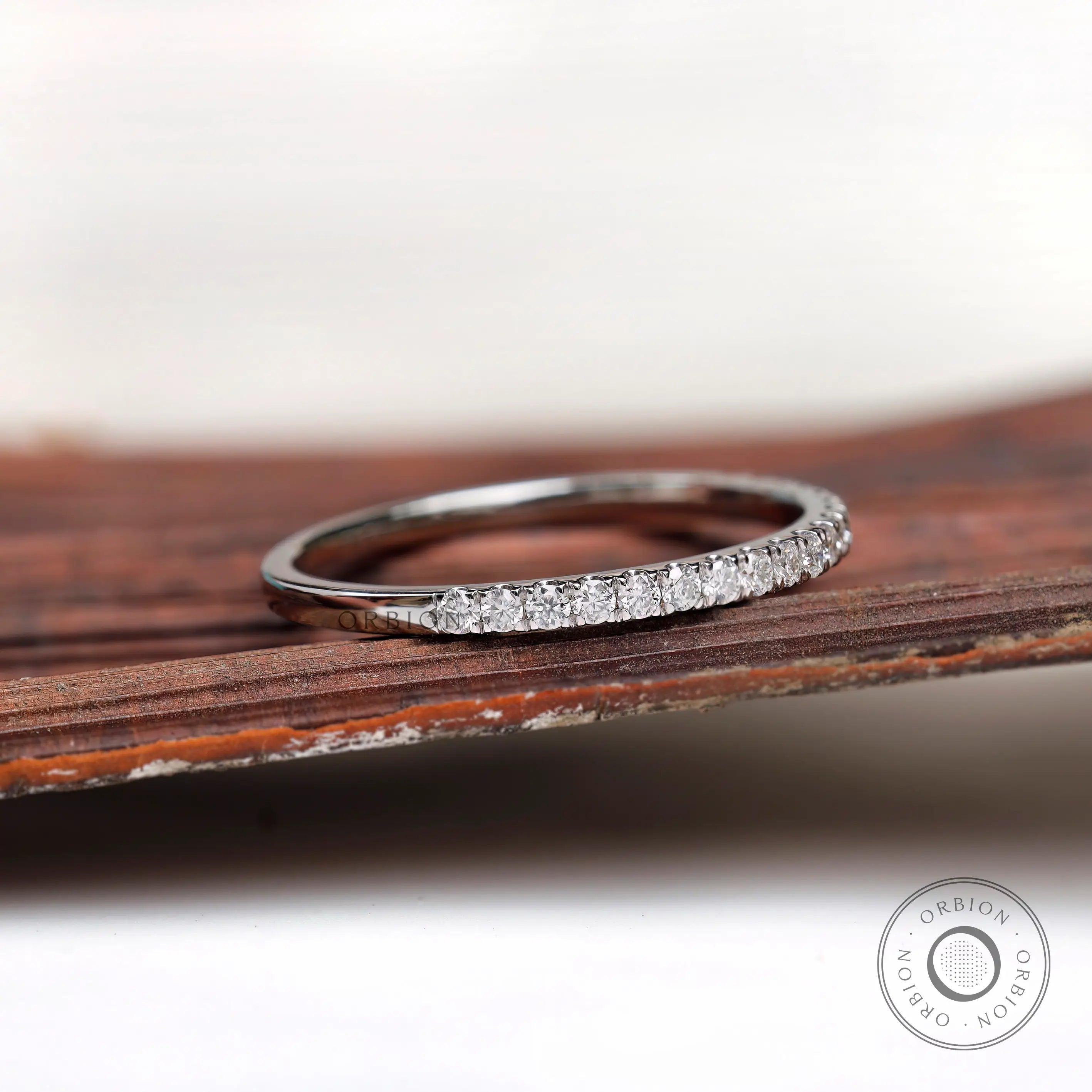 Angled view of minimalist pave wedding band with polished gold finish