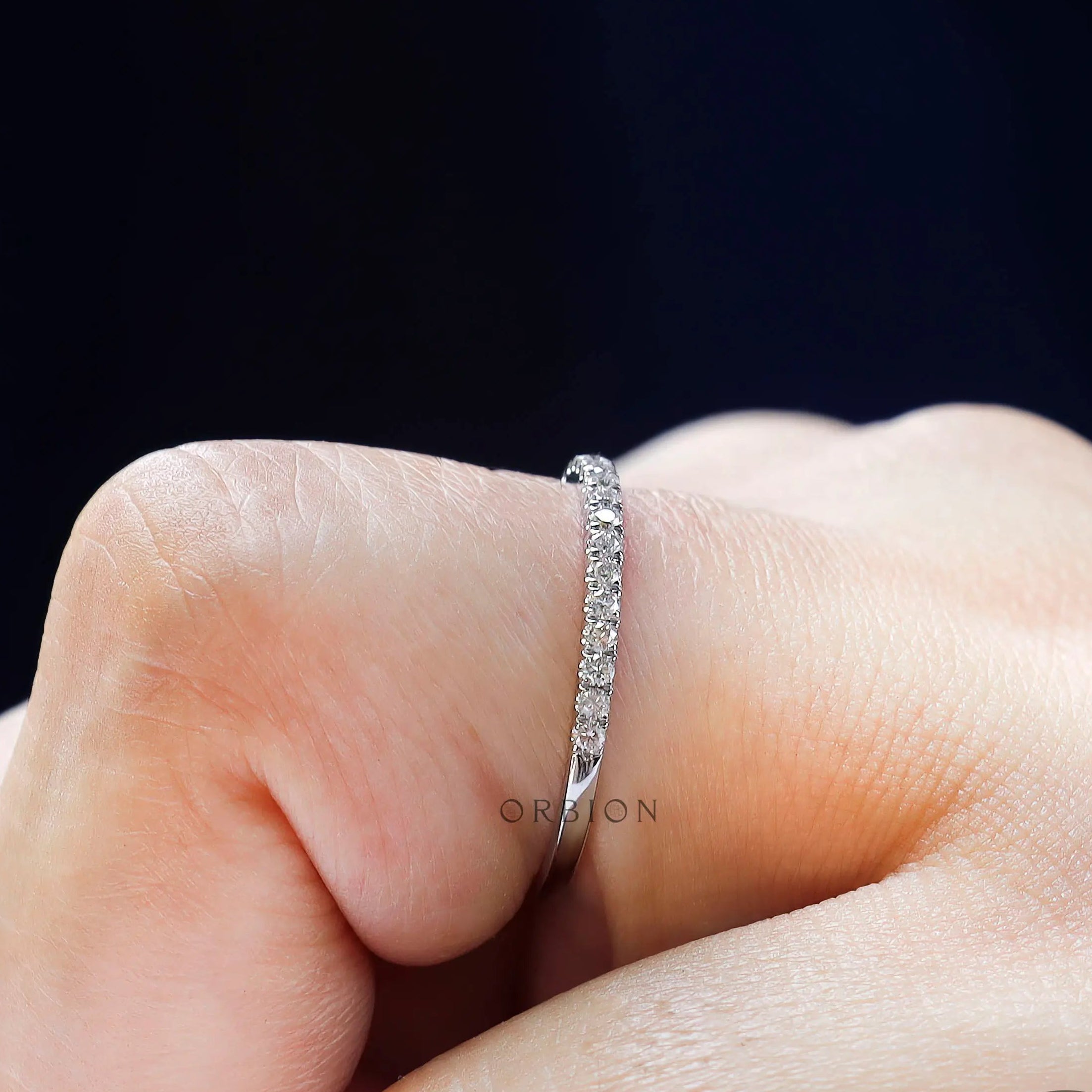 Worn on finger side view of dainty moissanite wedding band