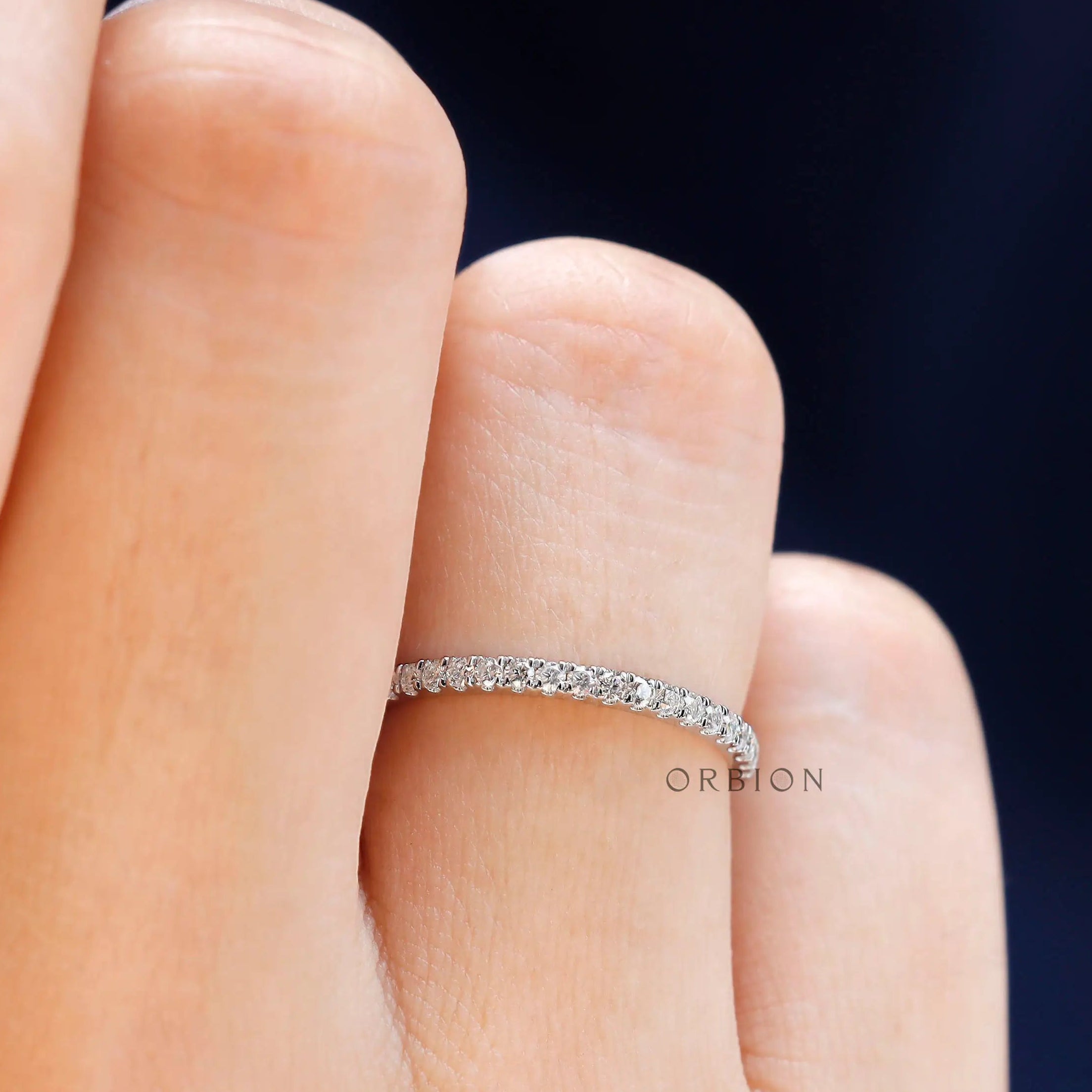 Close up view of the minimalist moissanite wedding band worn on finger