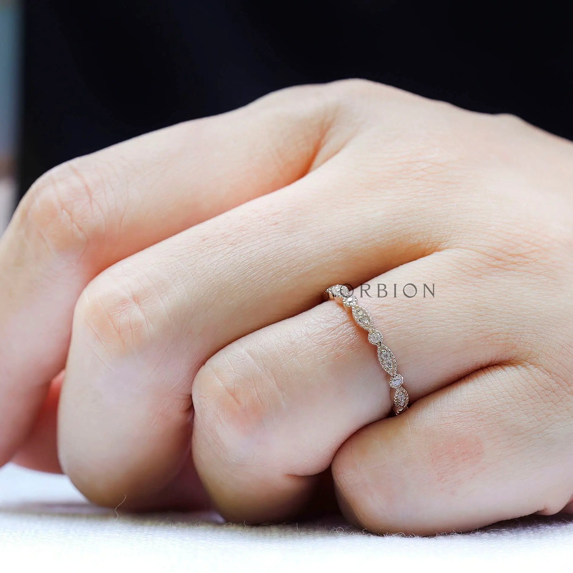 Slim marquise and round moissanite wedding band worn on hand