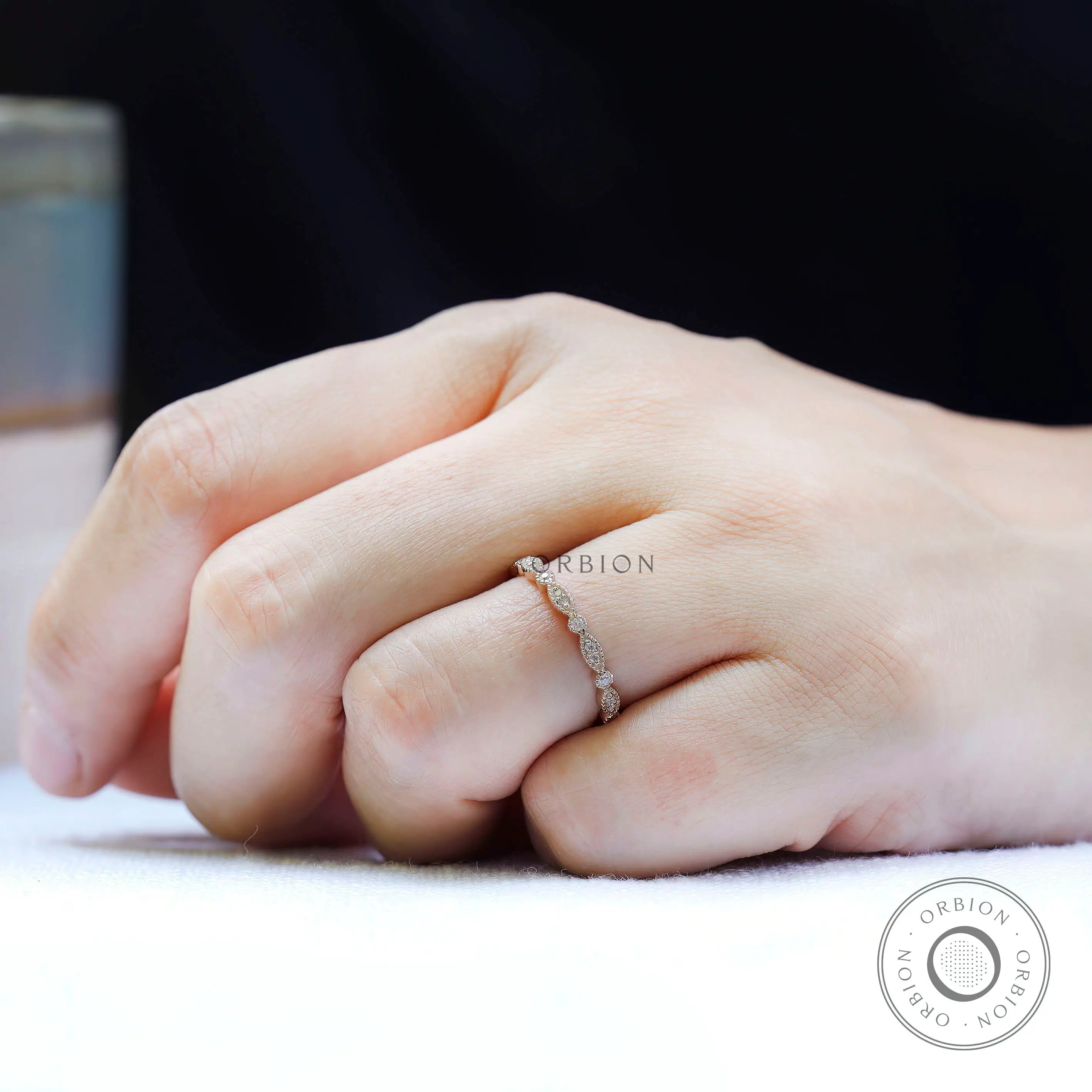 Slim marquise and round moissanite wedding band worn on hand