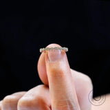Top view of geometric marquise and round moissanite band held on fingertip