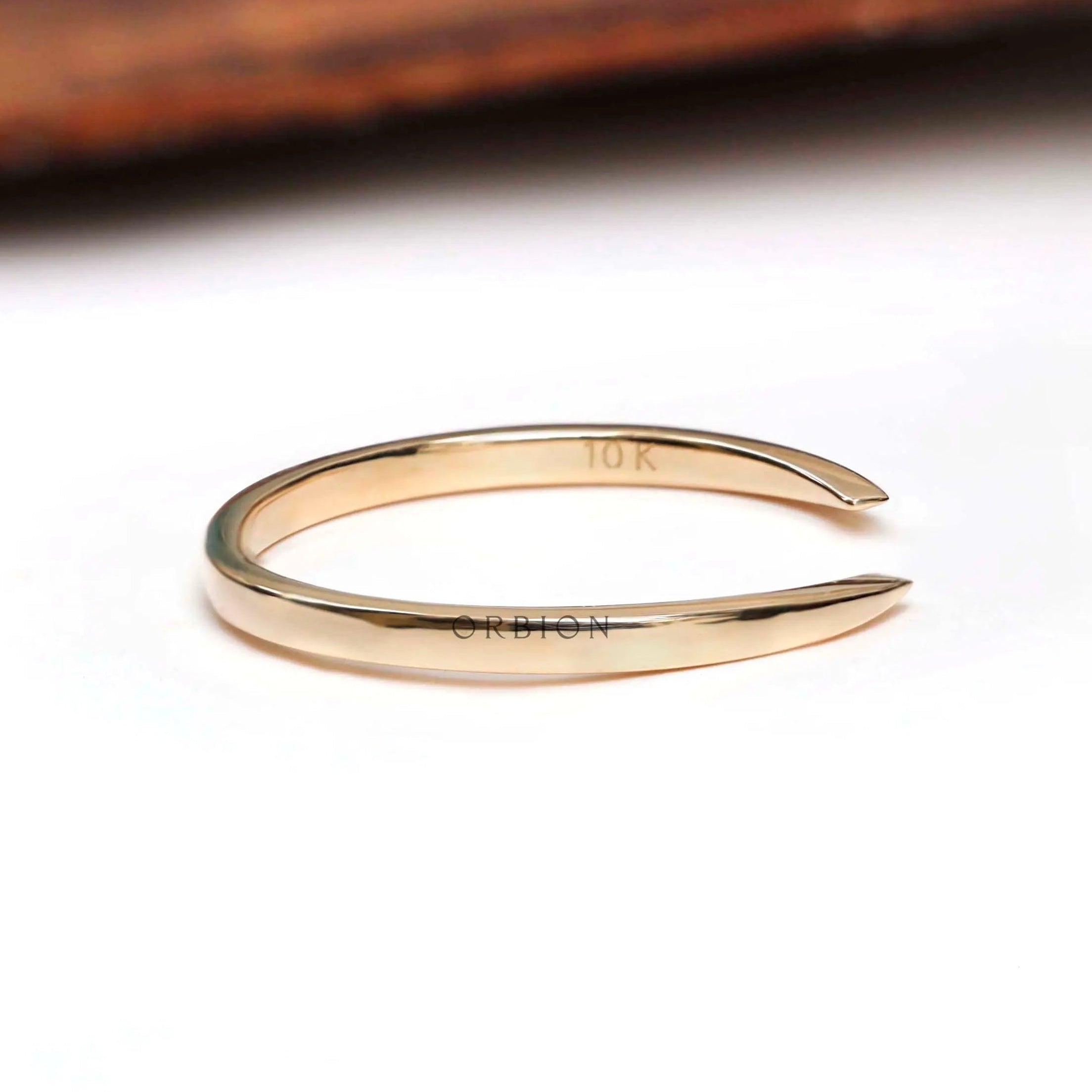 Side profile of solid gold open cuff wedding band showing tapered claw ends