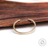 Minimalist open cuff gold wedding band styled on wooden surface