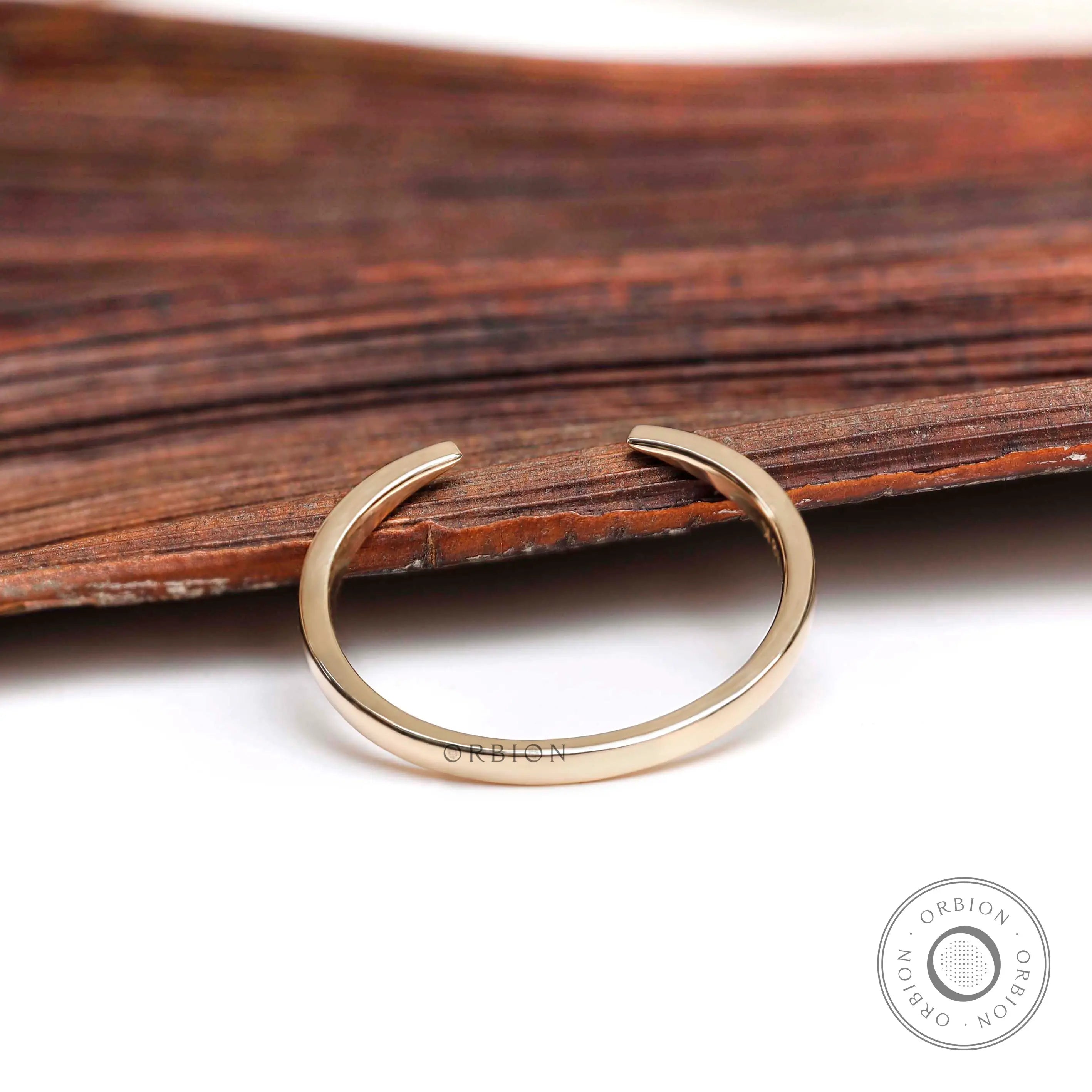 Minimalist open cuff gold wedding band styled on wooden surface
