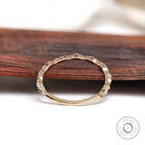 Thin bamboo style moissanite band on wooden surface