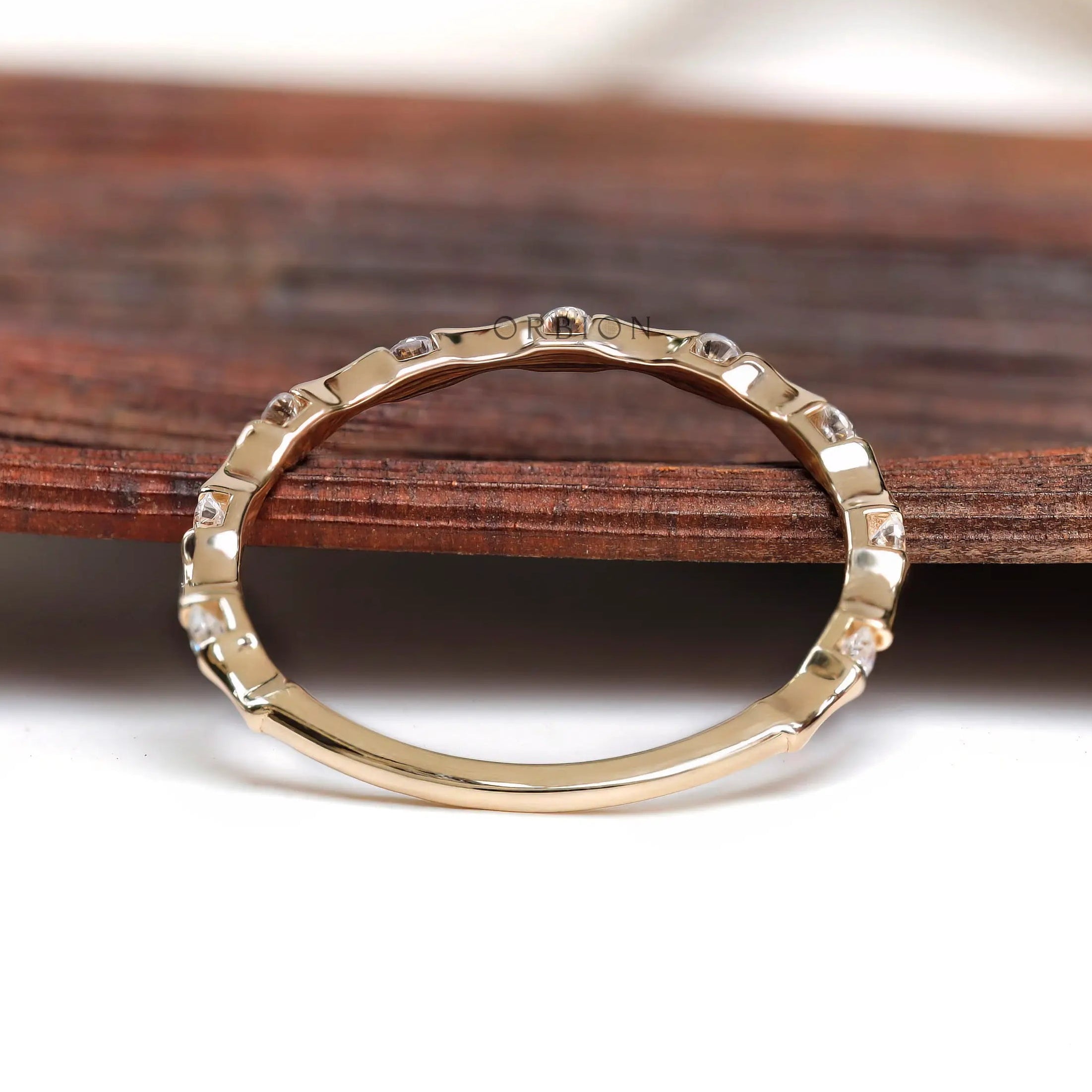 Thin bamboo style moissanite band on wooden surface