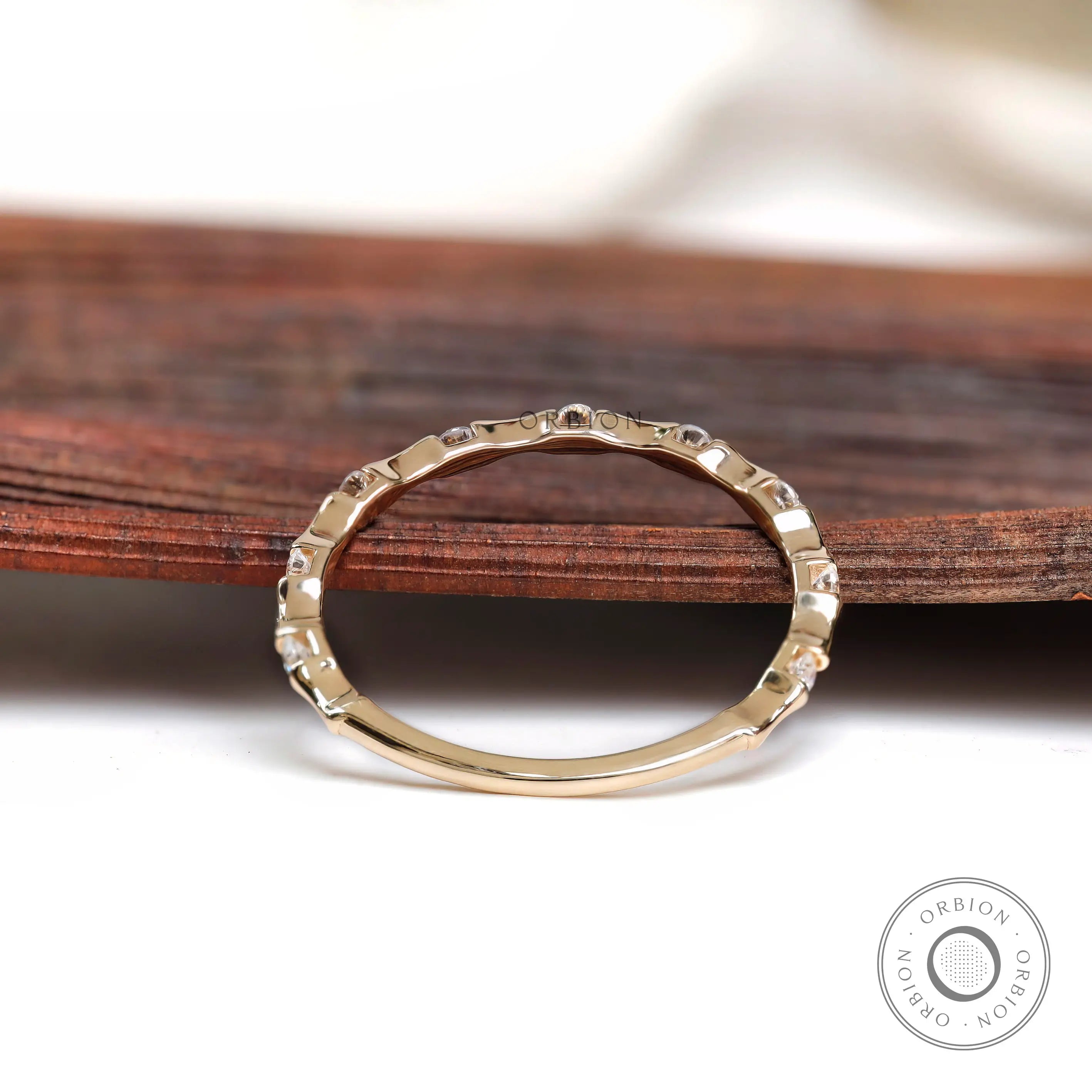 Thin bamboo style moissanite band on wooden surface