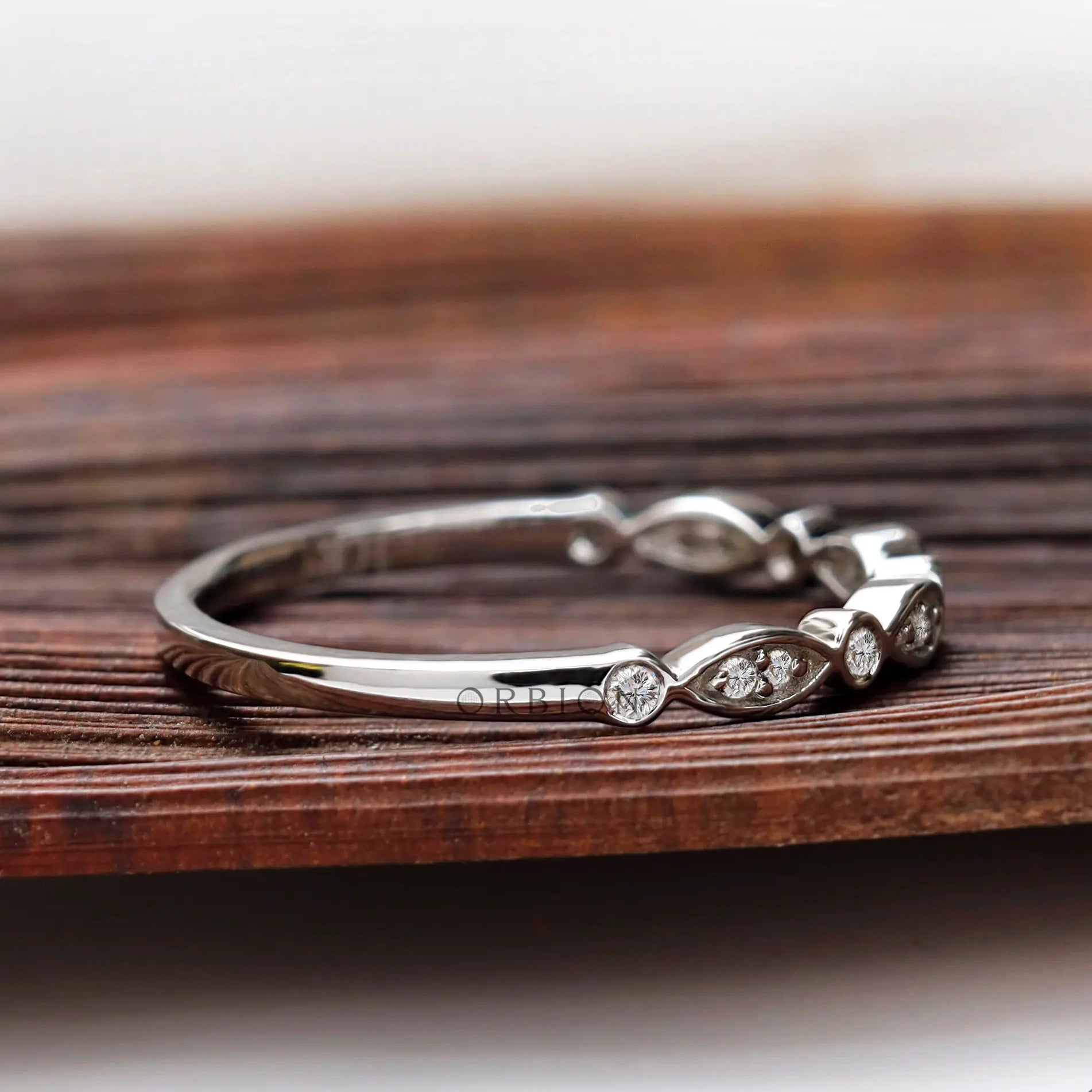 Angled side view of Art Deco inspired wedding band showing alternating marquise bezel-set.