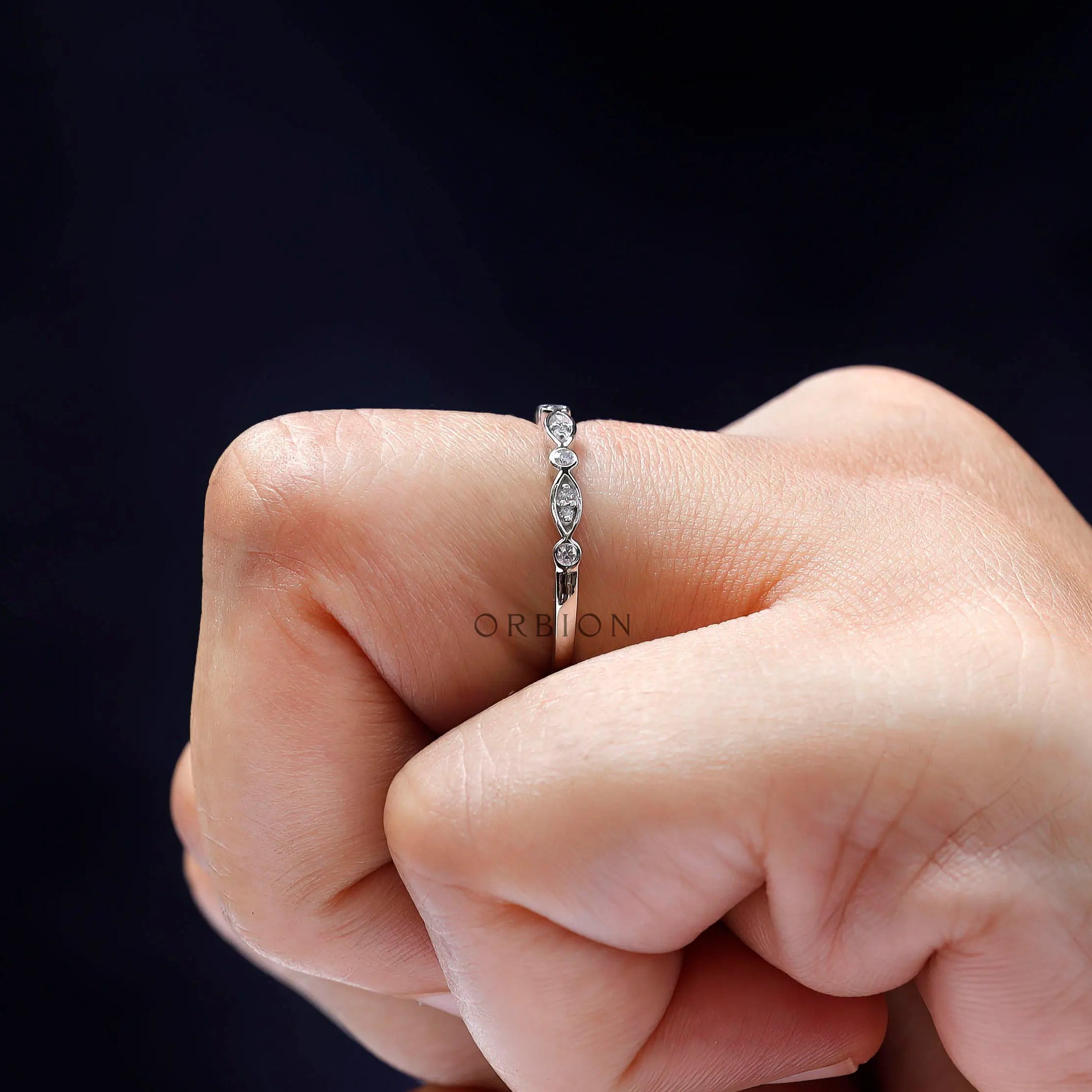 Close-up on finger showing marquise-and-round pattern of the half eternity band.