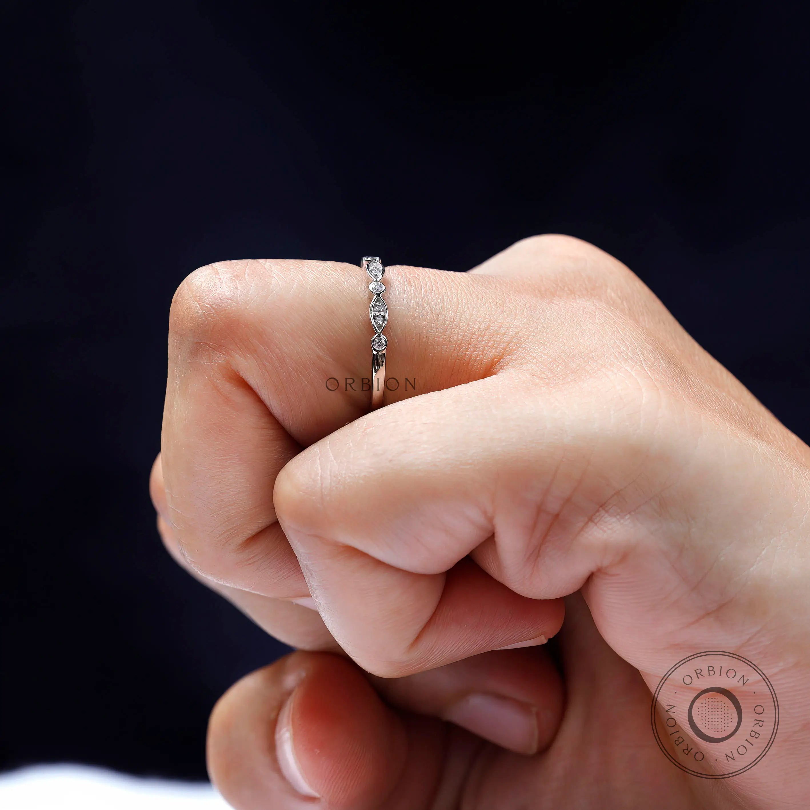 Close-up on finger showing marquise-and-round pattern of the half eternity band.