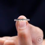 Close-up detail of vintage Art Deco moissanite band held between fingers.