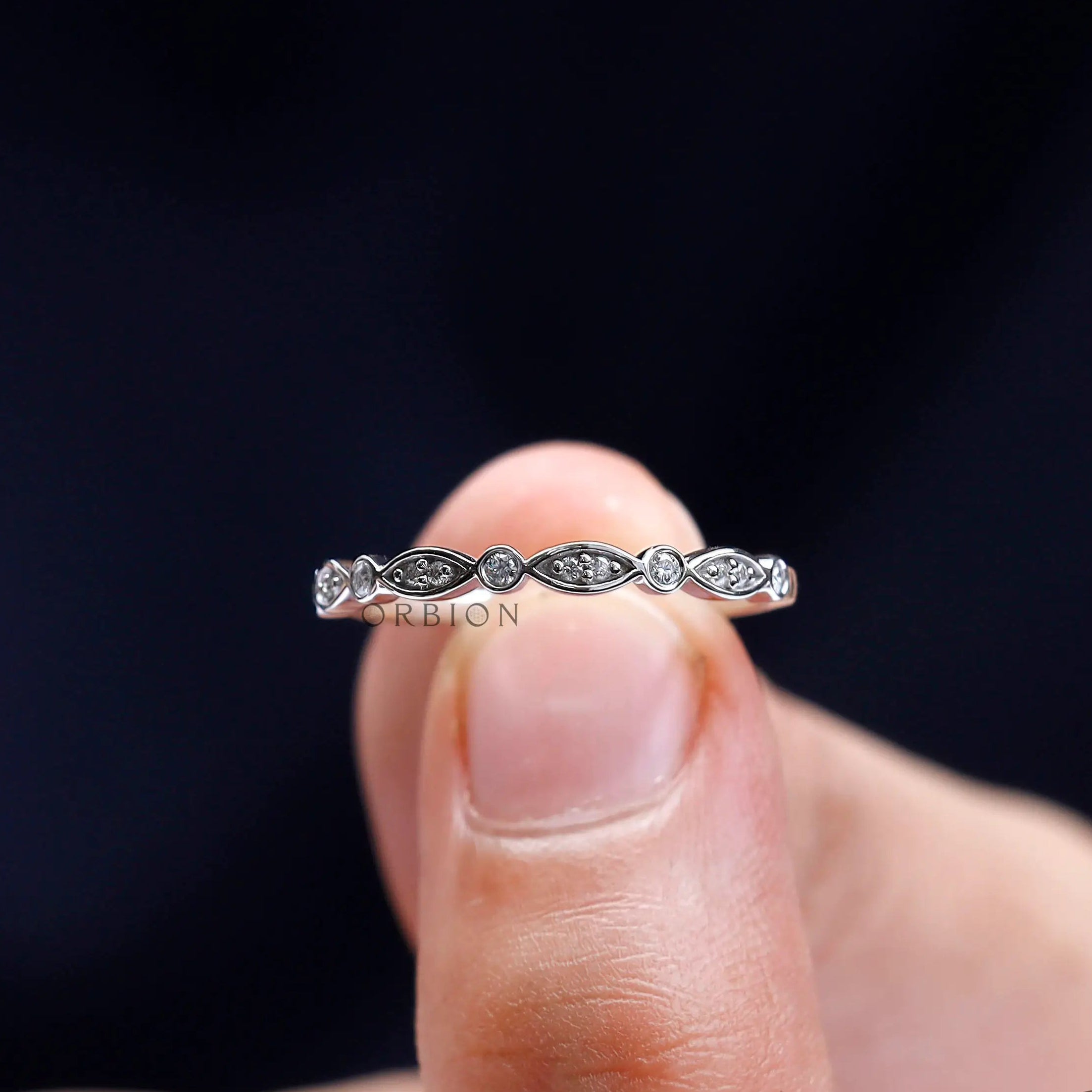 Close-up detail of vintage Art Deco moissanite band held between fingers.