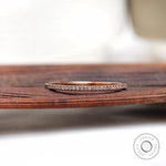 Pave moissanite half eternity wedding band resting on wooden surface