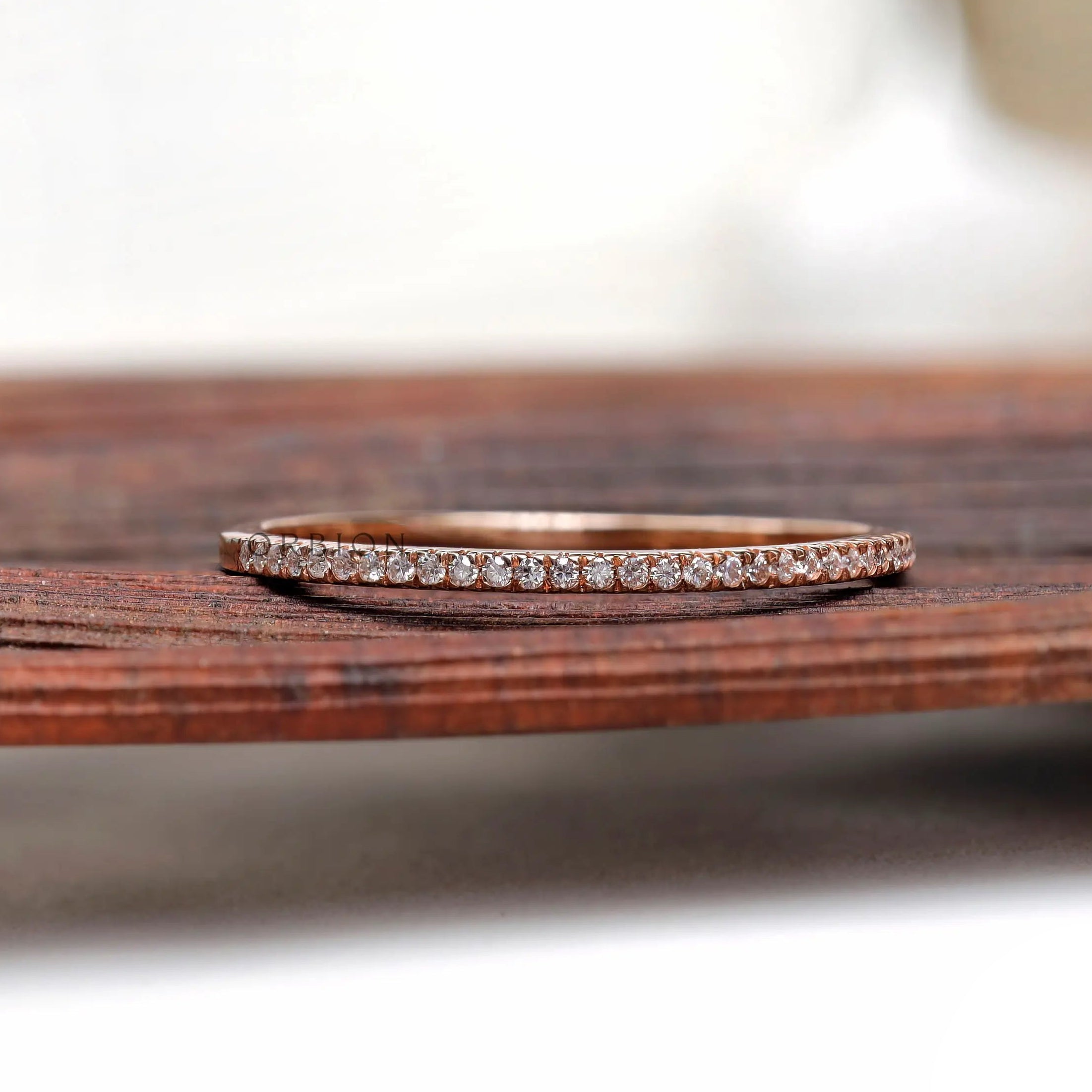 Pave moissanite half eternity wedding band resting on wooden surface
