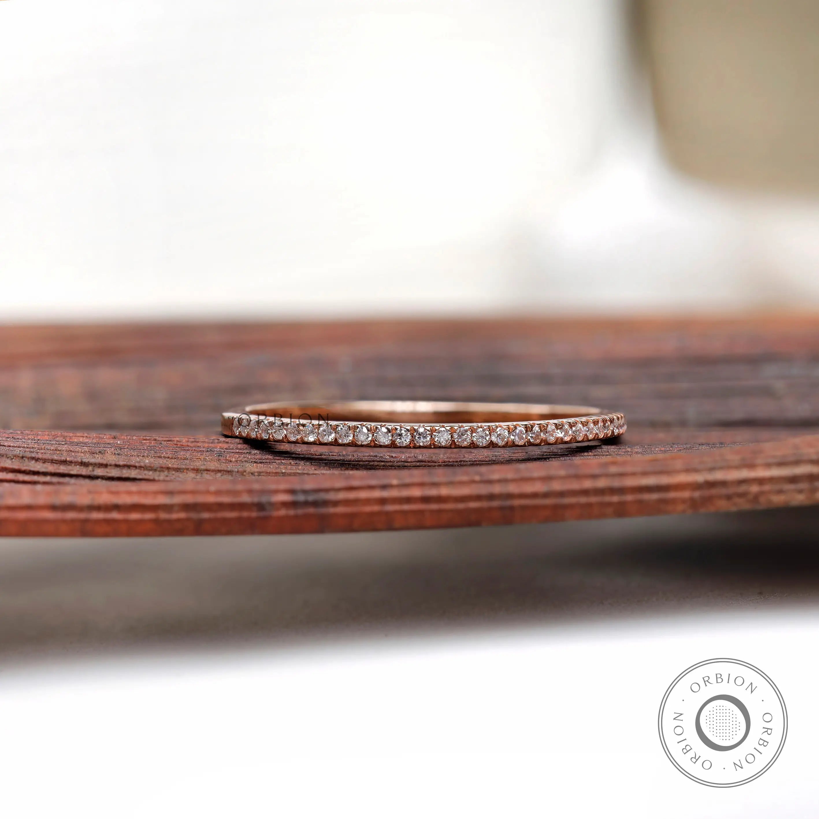 Pave moissanite half eternity wedding band resting on wooden surface
