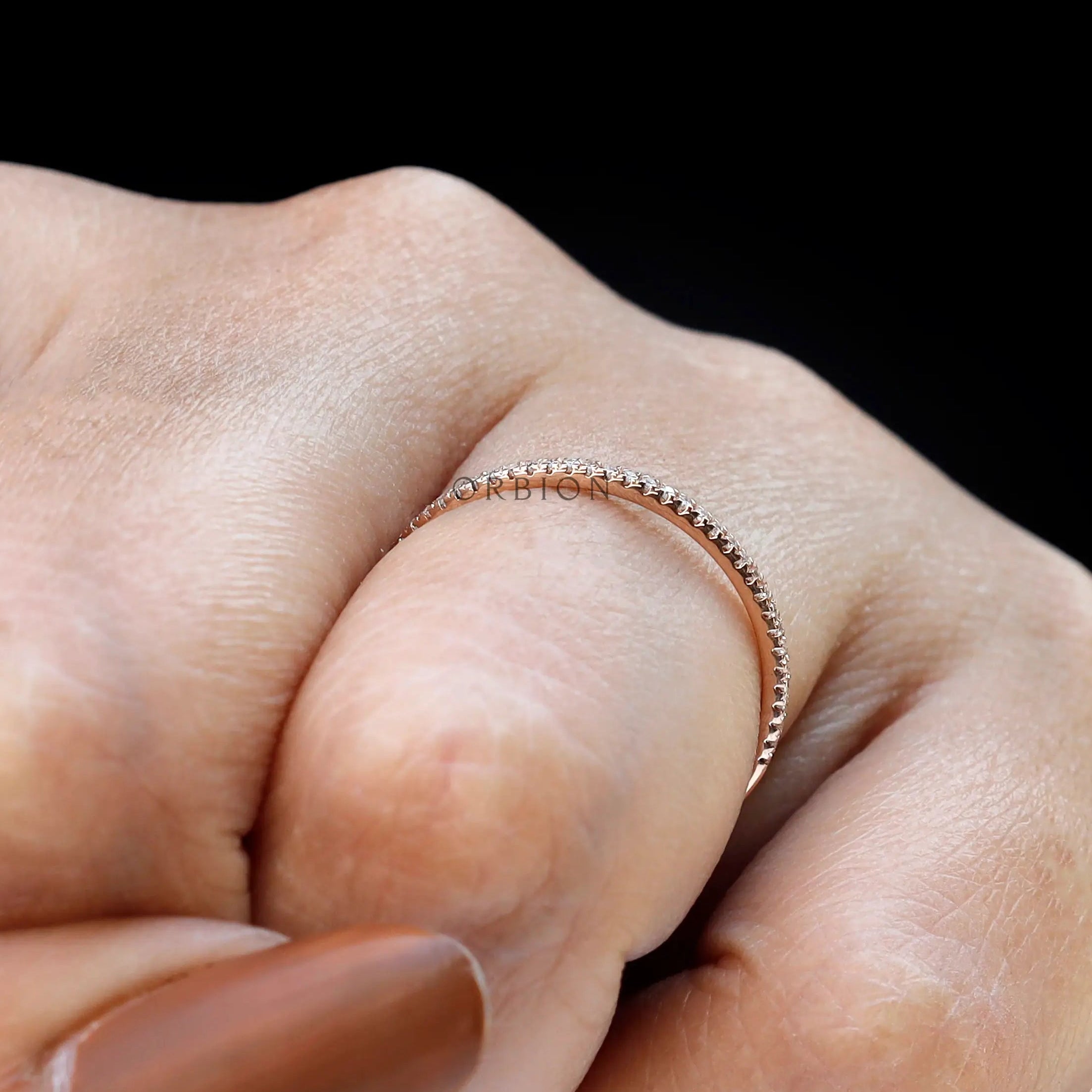 Minimal pave moissanite half eternity band worn on finger close-up