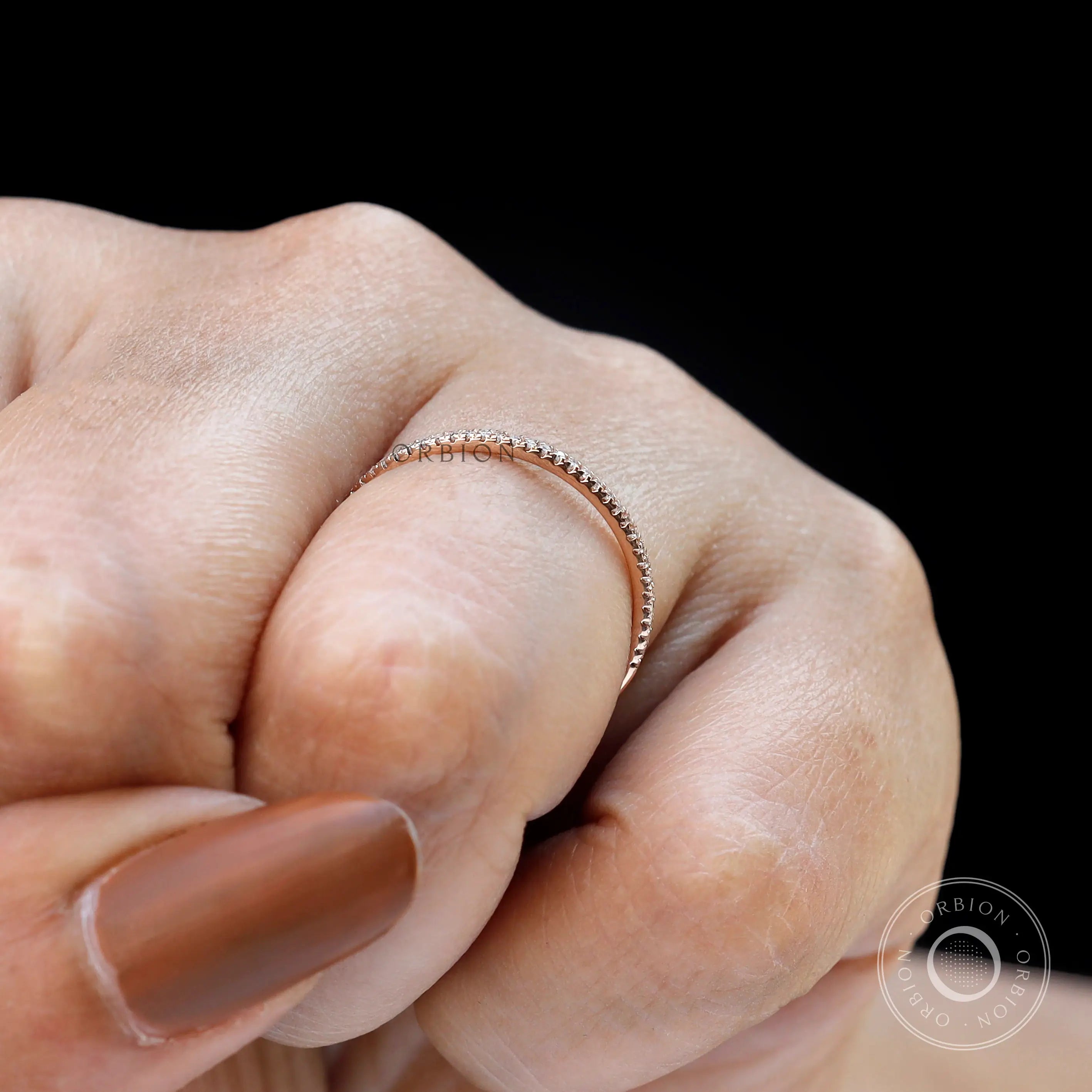 Minimal pave moissanite half eternity band worn on finger close-up
