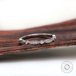 Front view of delicate geometric eternity band with oval and bezel-set round accents.