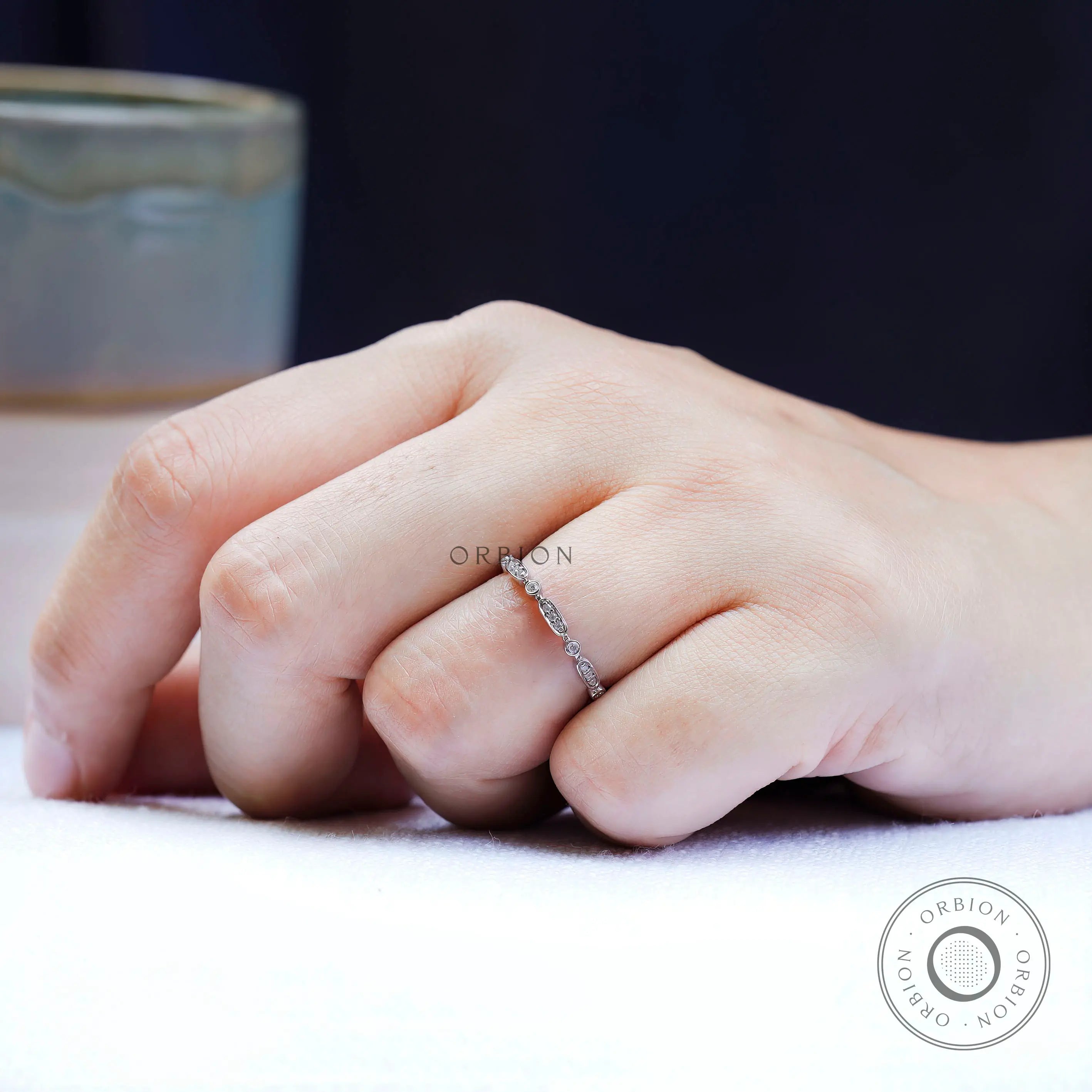 Angled on-hand view showing the sparkle of bezel-set round accents and oval.