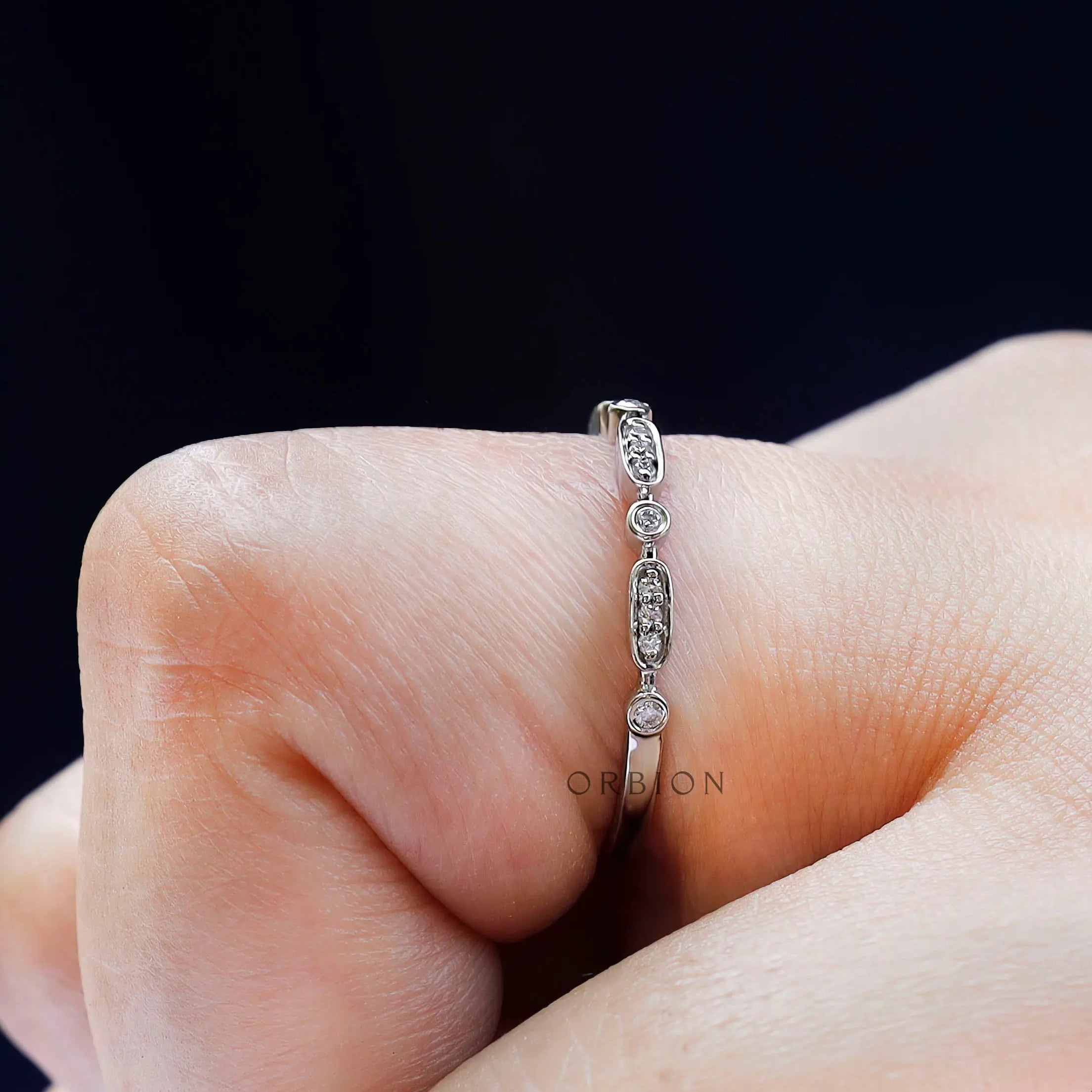 Close-up on finger showing the geometric pattern with round bezel accents.