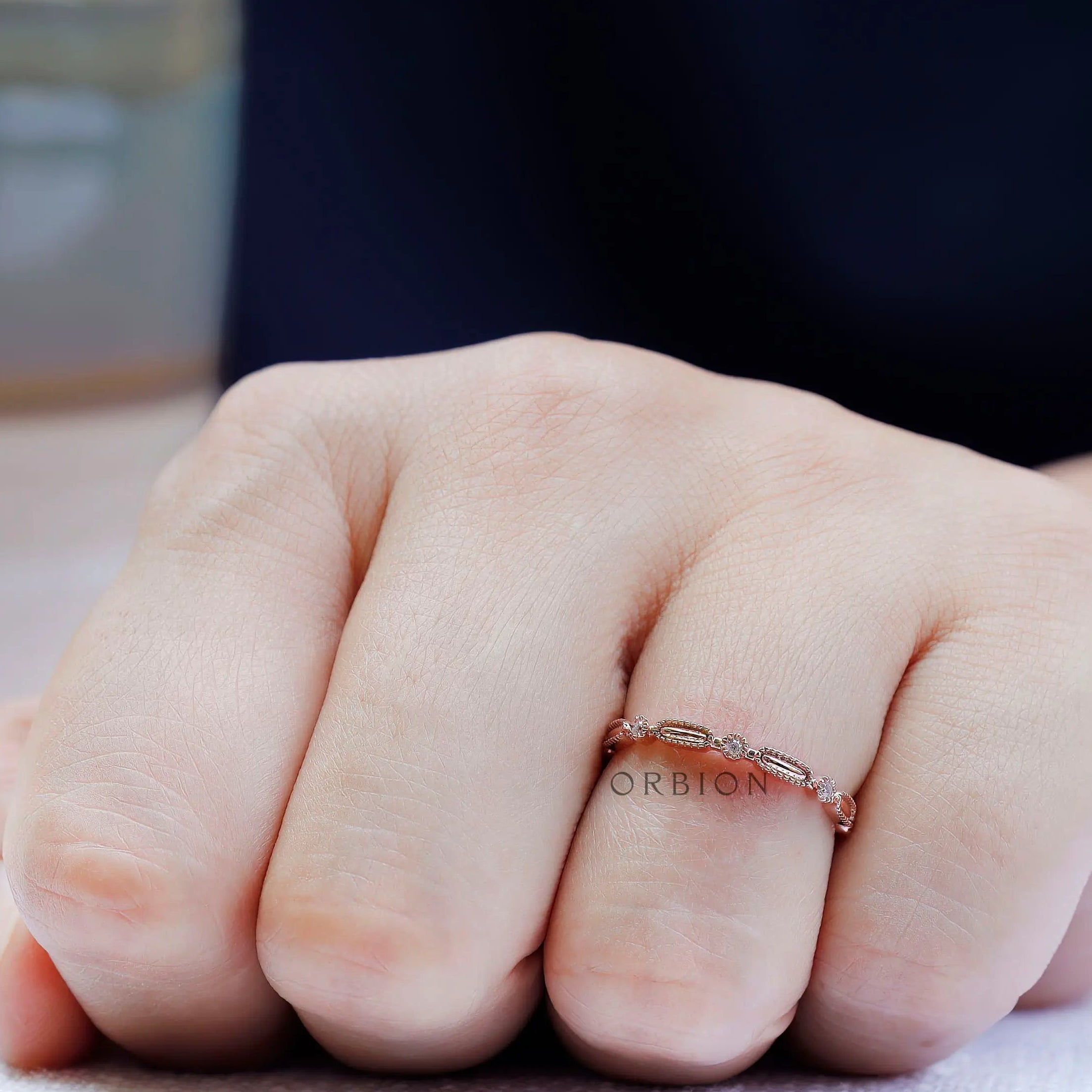 On-hand view delicate geometric textured wedding band in rose gold