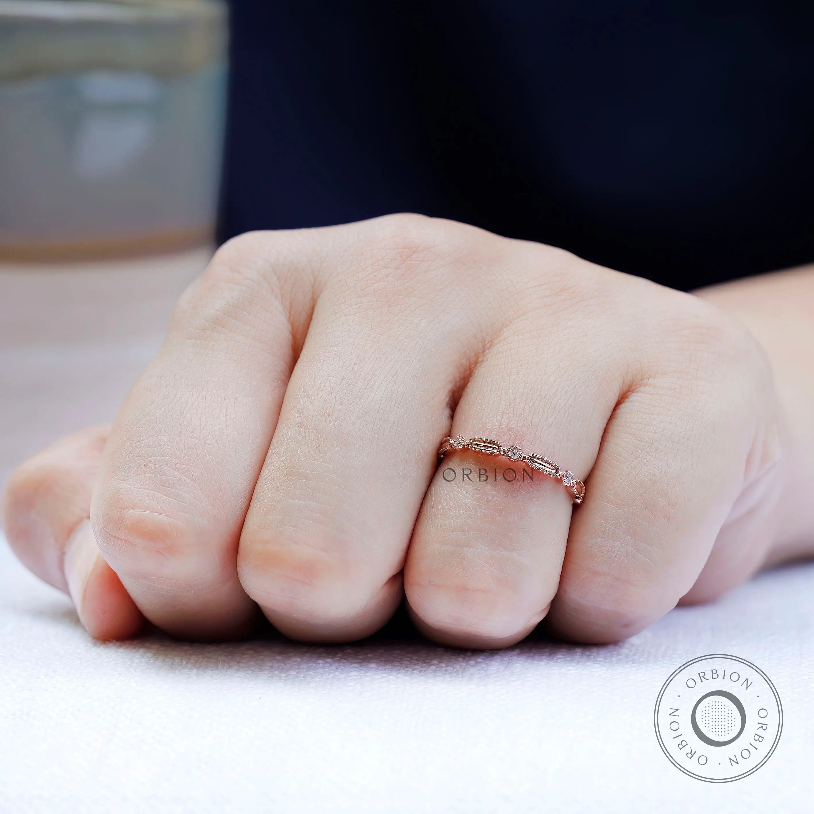On-hand view delicate geometric textured wedding band in rose gold