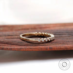 Angled side view showing bezel set stones and smooth yellow gold band.