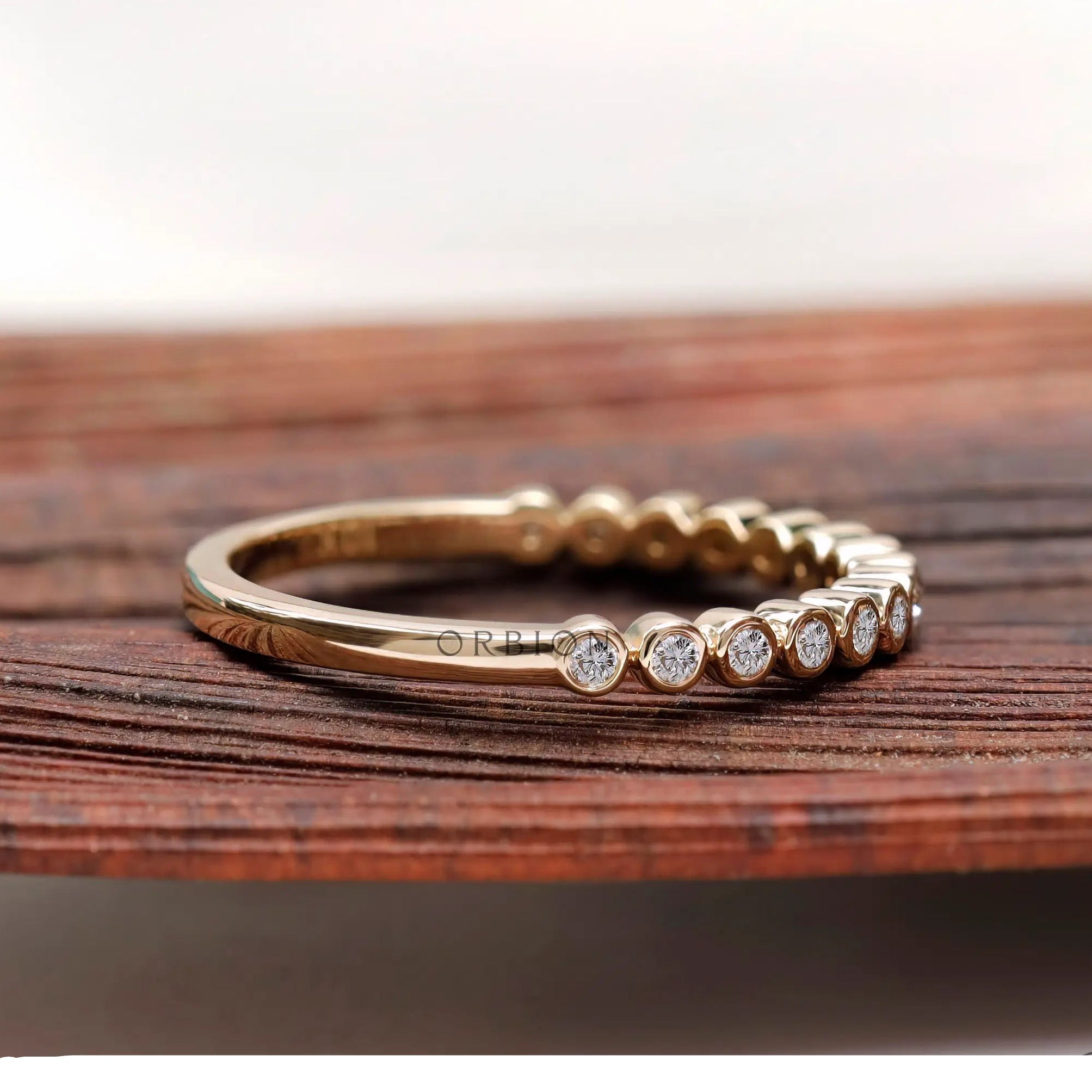 Angled side view showing bezel set stones and smooth yellow gold band.