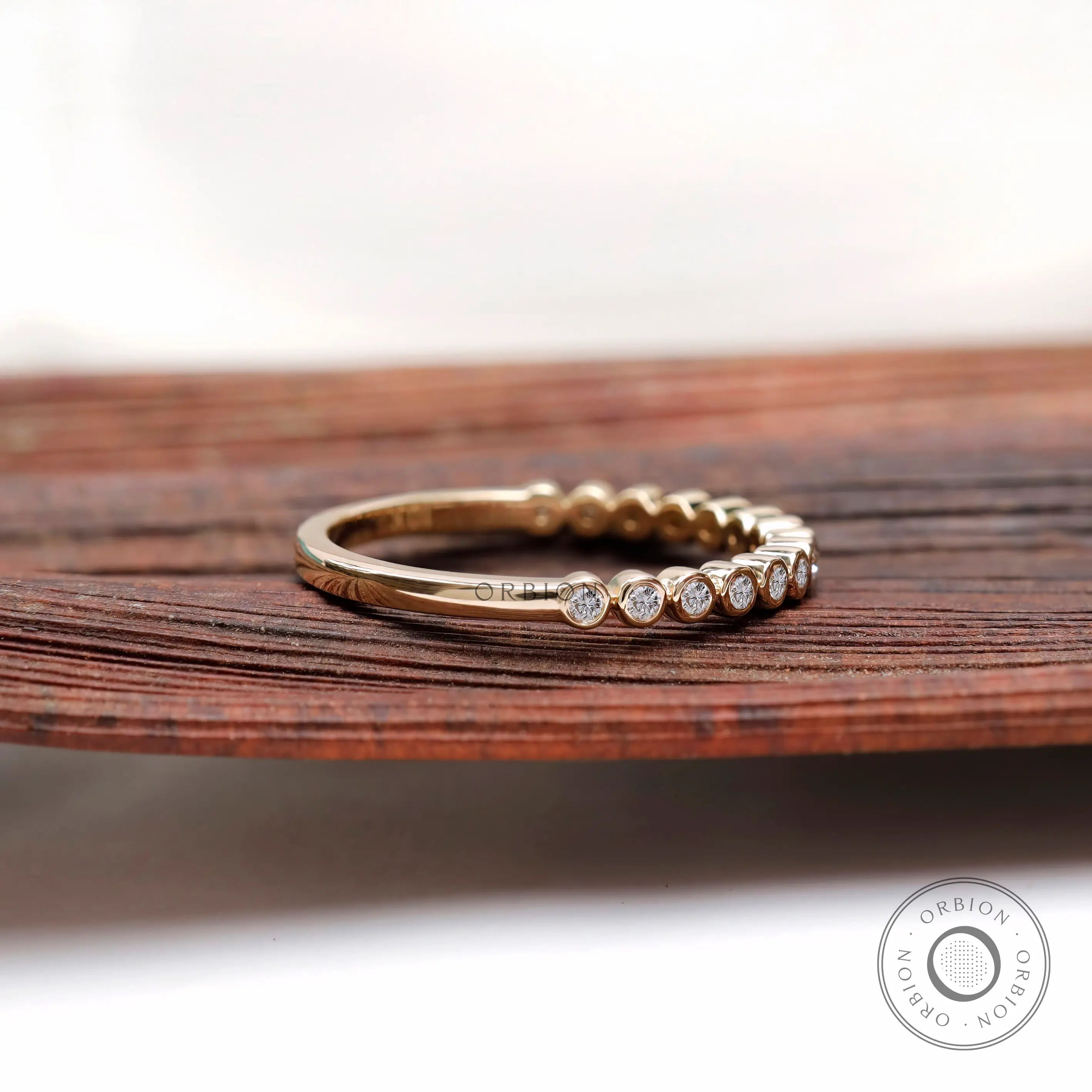 Angled side view showing bezel set stones and smooth yellow gold band.