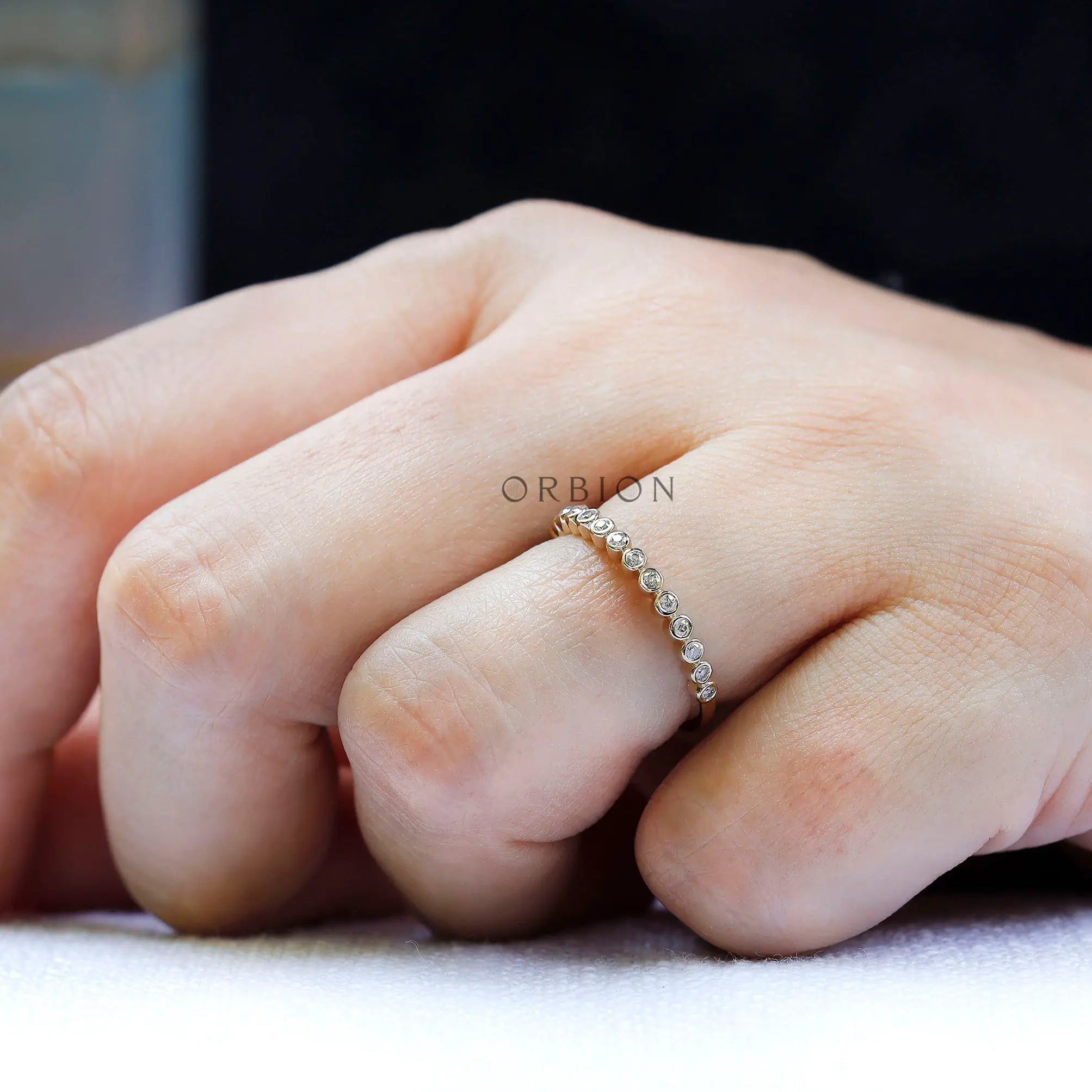 Lifestyle image of dainty bubble half eternity band worn on hand.