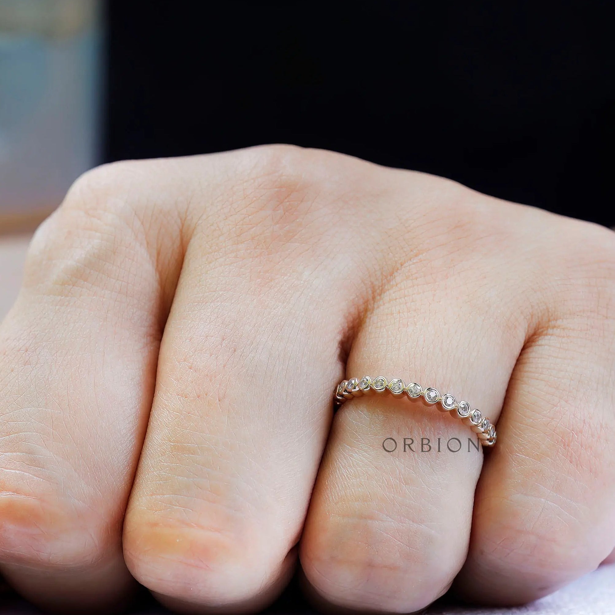 Top view on hand showing evenly spaced bezel set round moissanite.