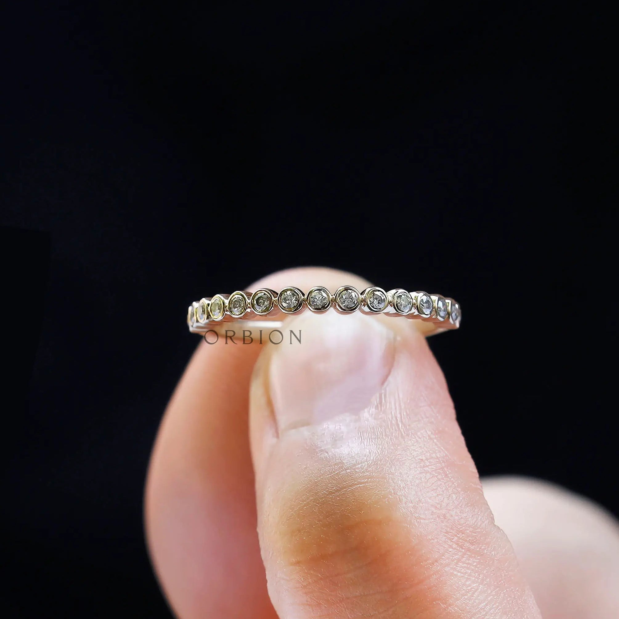 Close up of bubble half eternity band held between fingers.