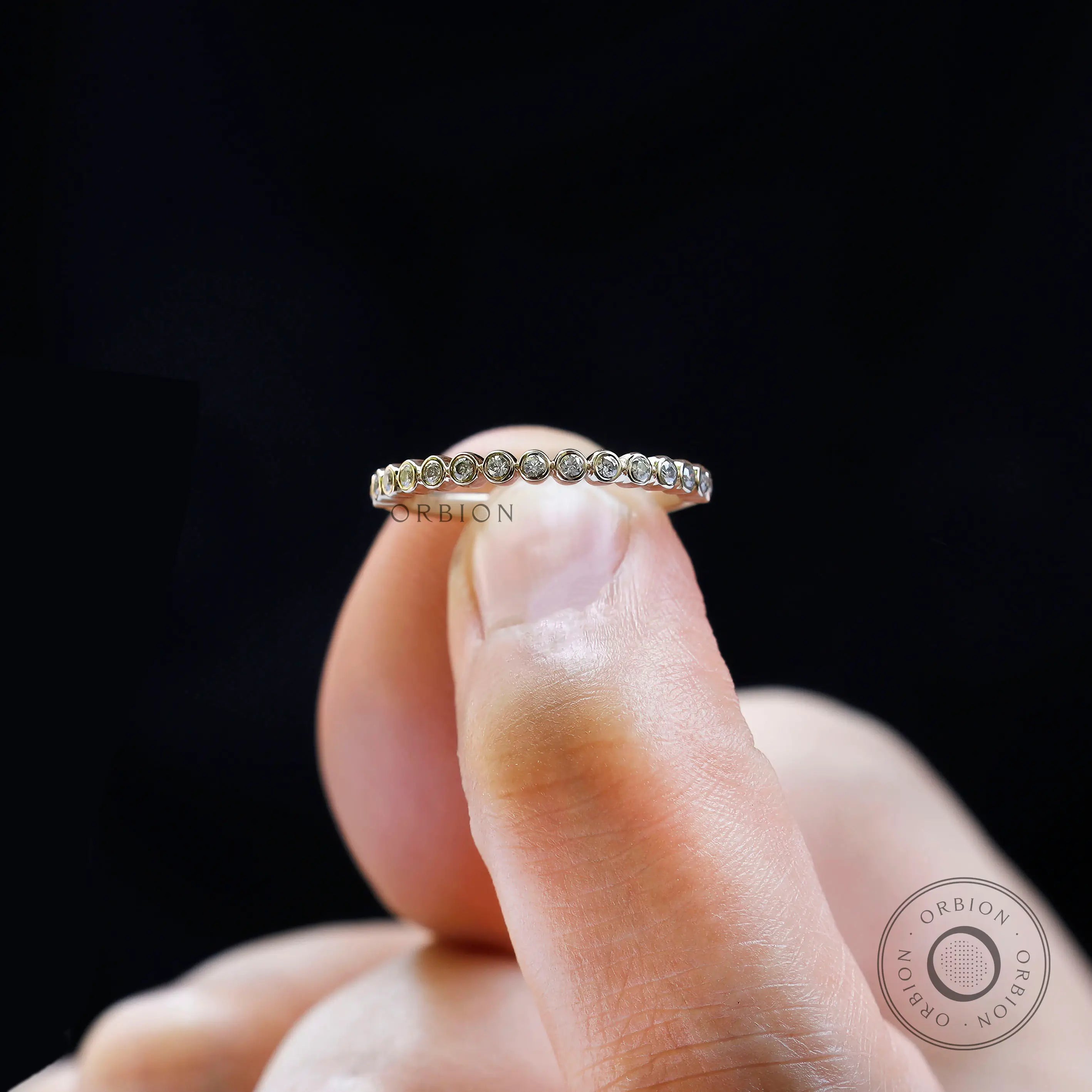 Close up of bubble half eternity band held between fingers.