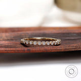 Half eternity bezel set moissanite band displayed on wooden surface front view